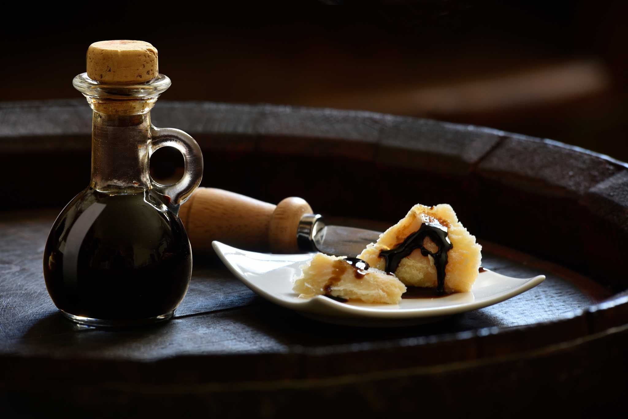 A jar of aceto balsamico with cheese, which has the balsamico sprinkled over it.