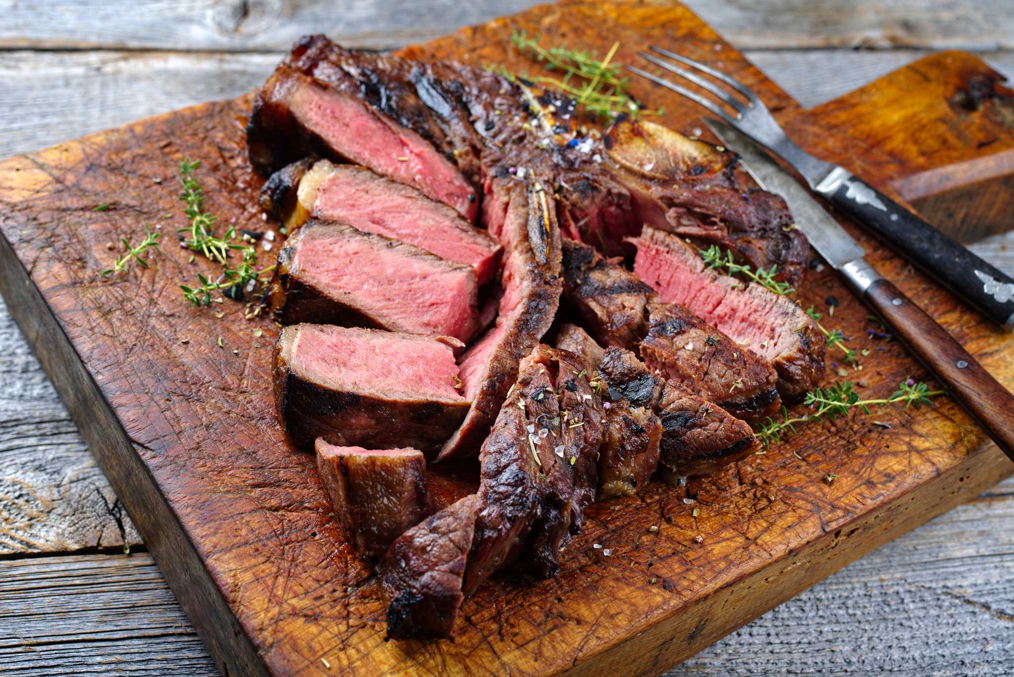 Bistecca alla fiorentina, a thick-cut t-bone steak on a table seasoned with salt and rosemary.