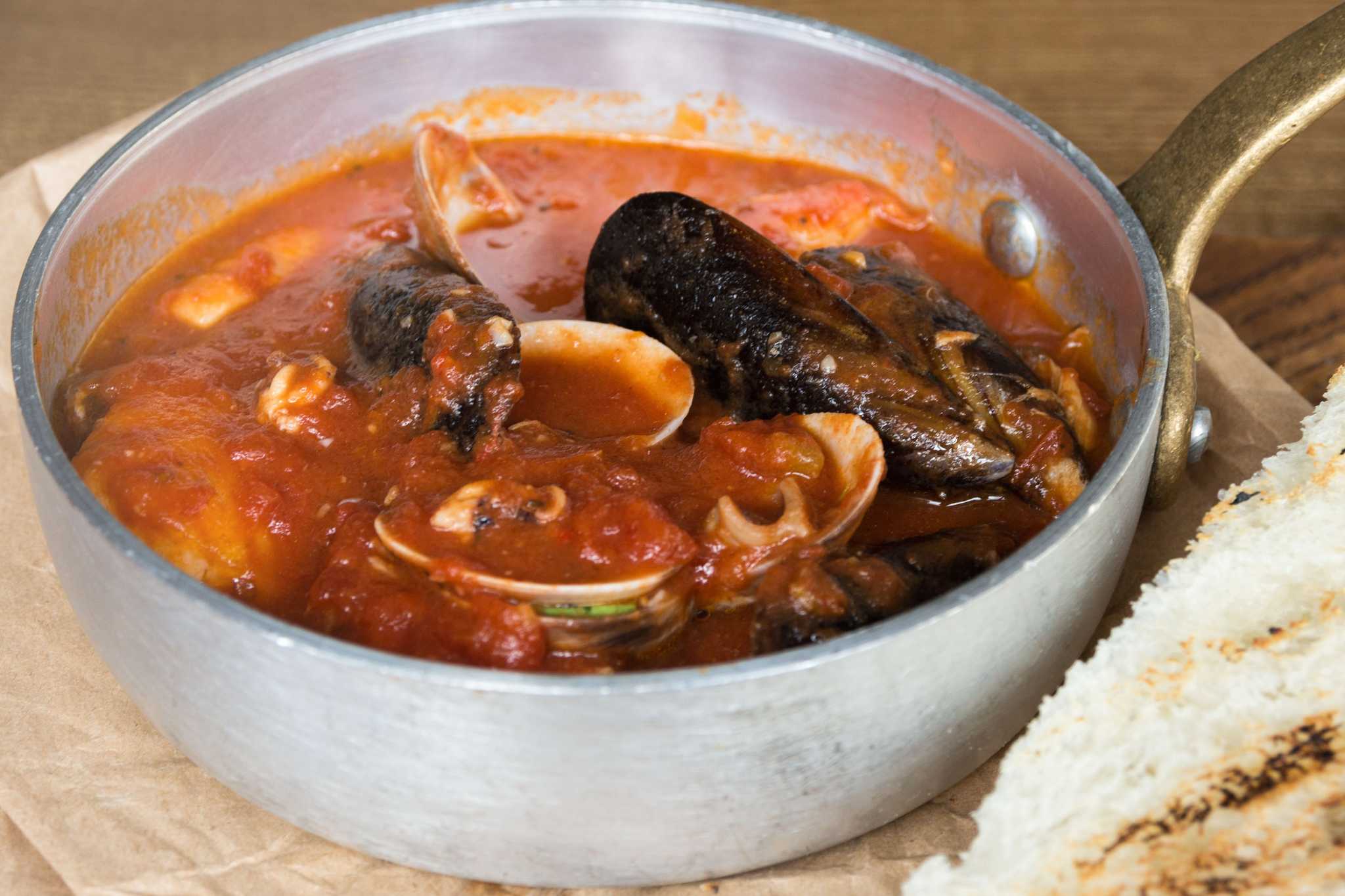 Cacciucco, a five-fish stew that comes from Emilia-Romagna, served in a bowl on a table.