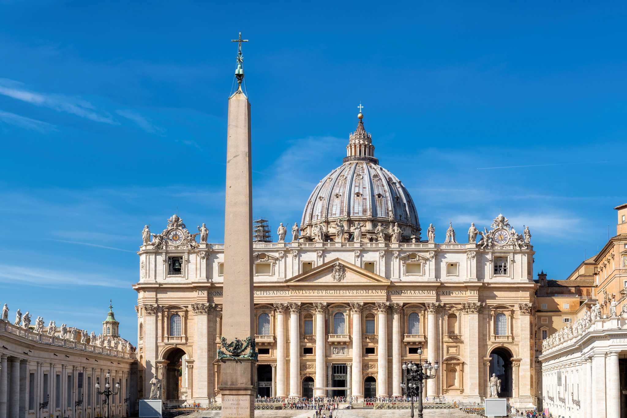 St. Peter's Basilica and its dome rising behind the obelisk on the sunlit square.