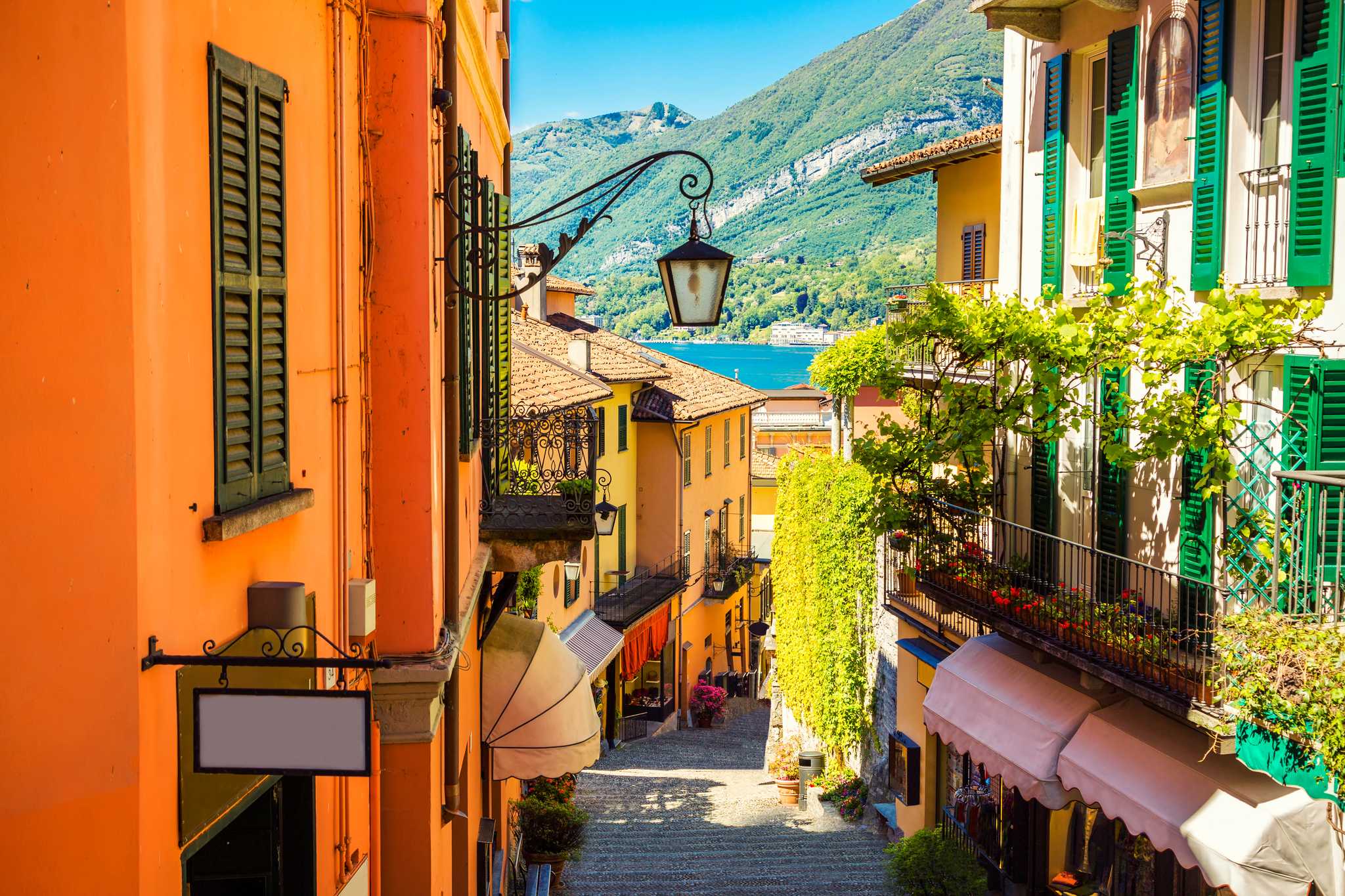 A stepped cobblestone street in Bellagio lined with colorful houses, descending toward Lake Como.