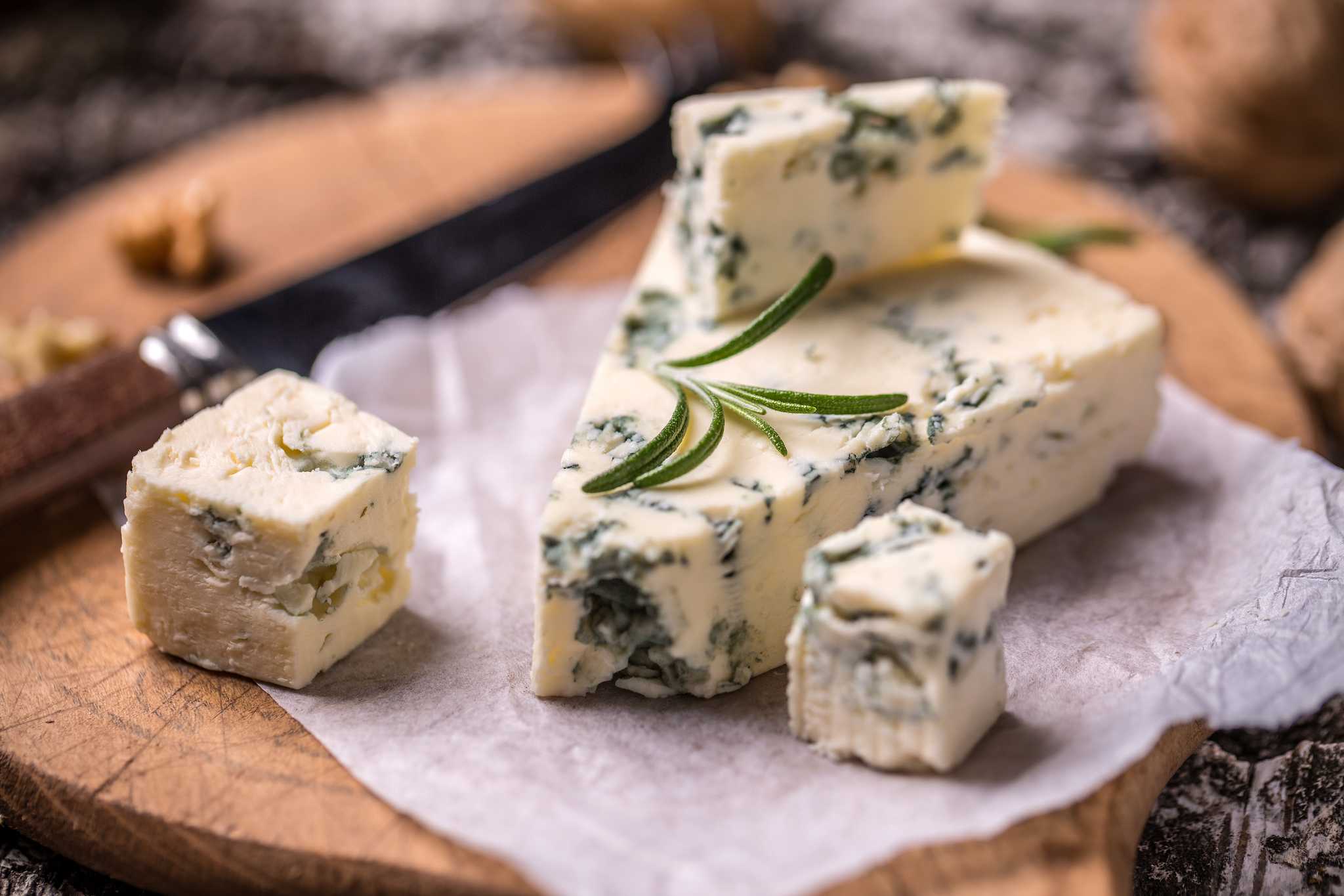 A wedge of blue-veined cheese with a sprig of rosemary on top.