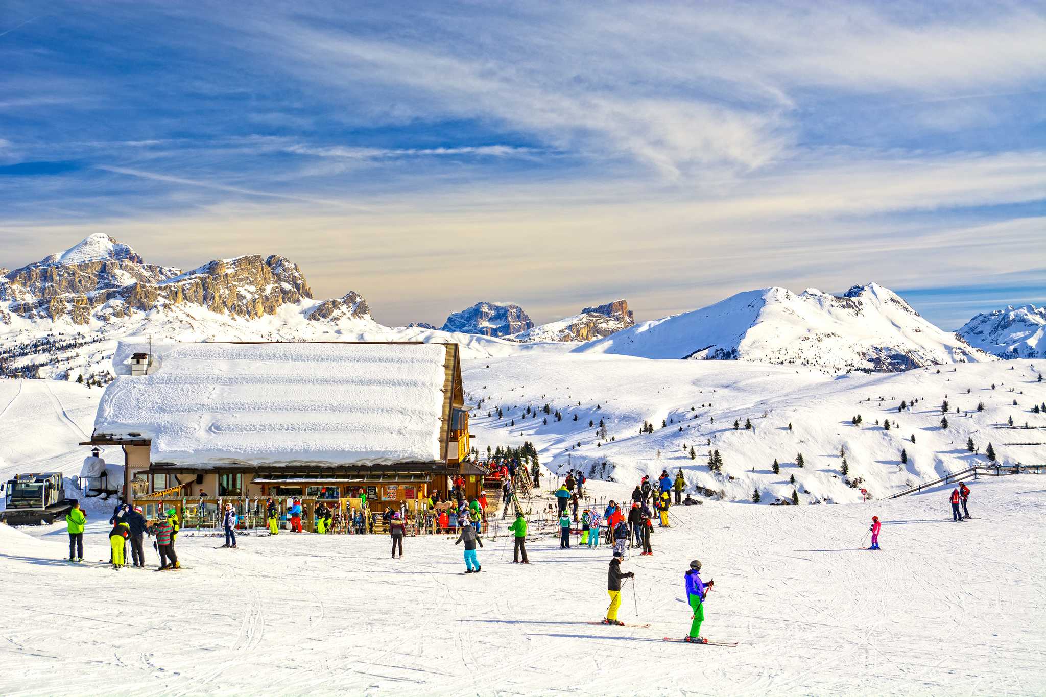 Skiers gather by a snow-covered mountain hut on the Sella Ronda circuit.