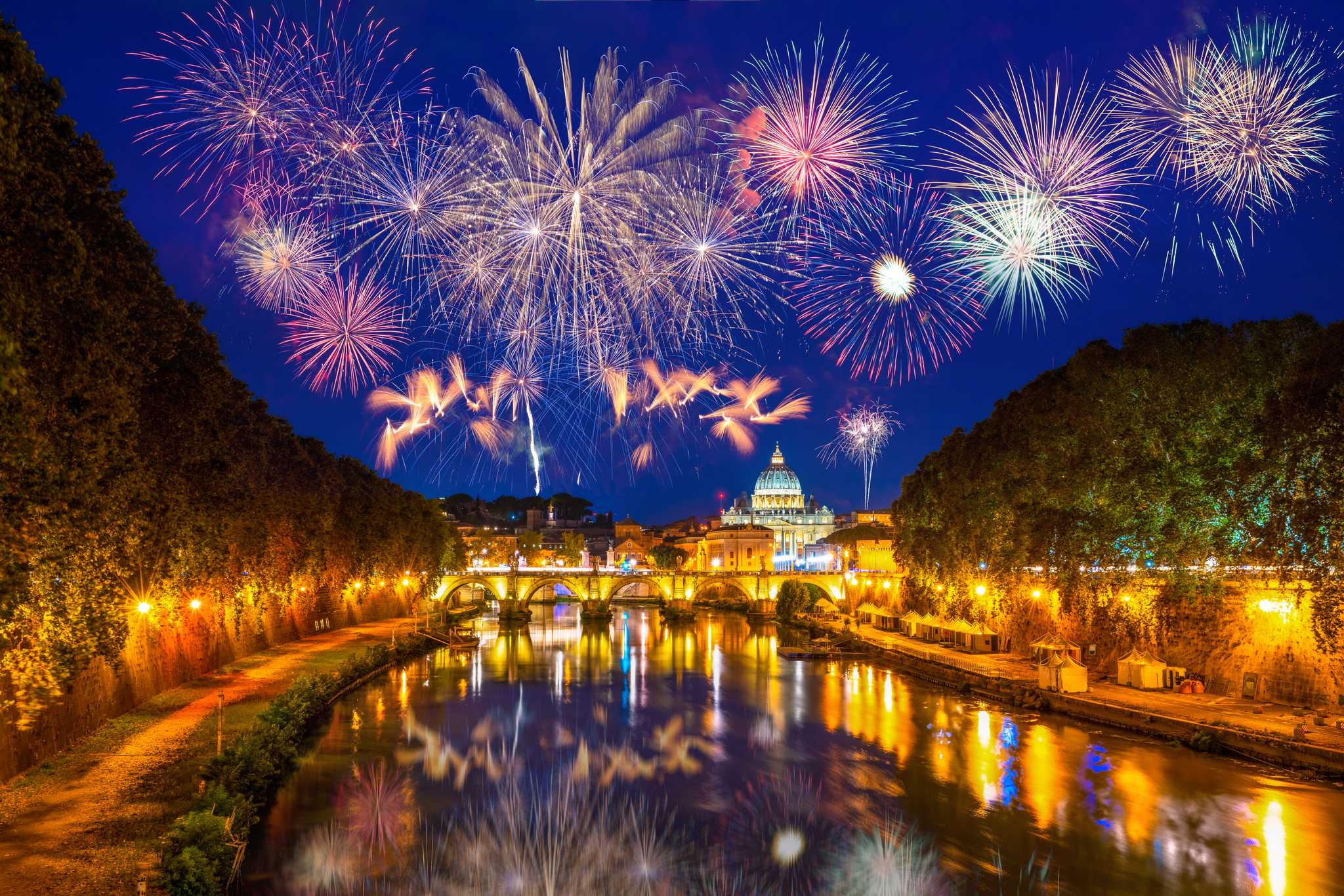 Fireworks above St. Peter's Basilica and the Tiber River in Rome at night.