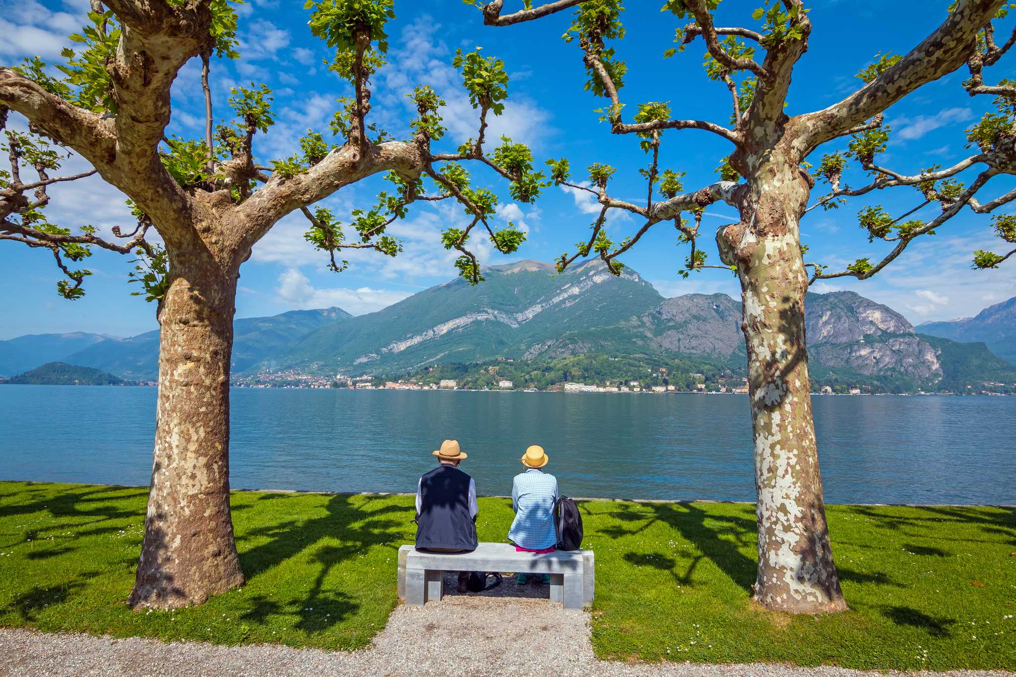 Senior couple on a bench in the Villa Melzi gardens overlooking Lake Como.