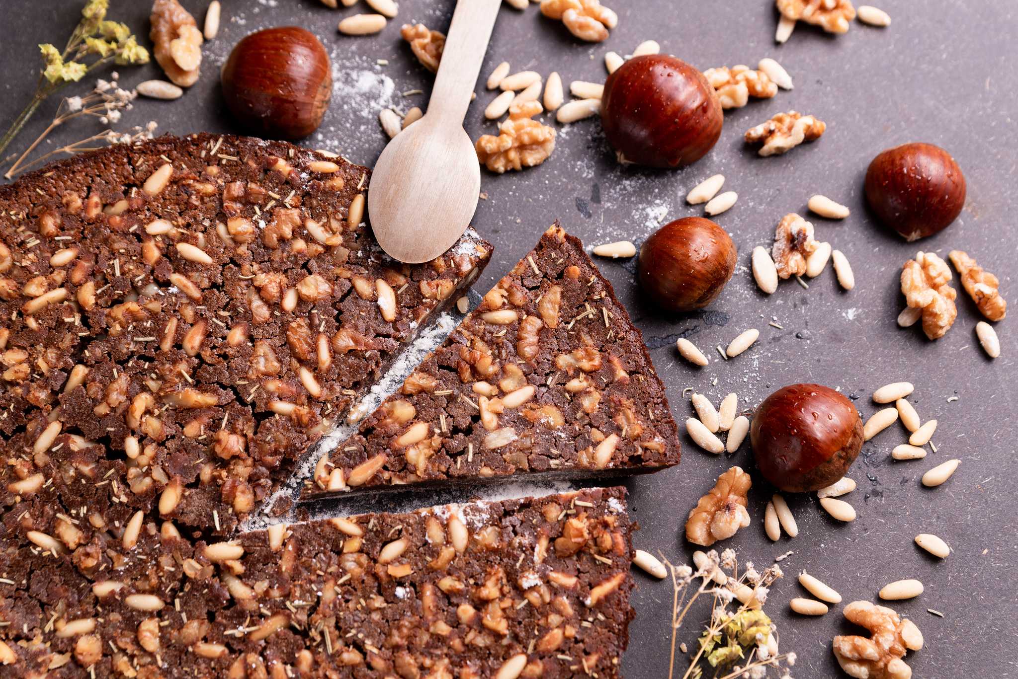 Slices of castagnaccio chestnut cake with pine nuts, walnuts and rosemary.