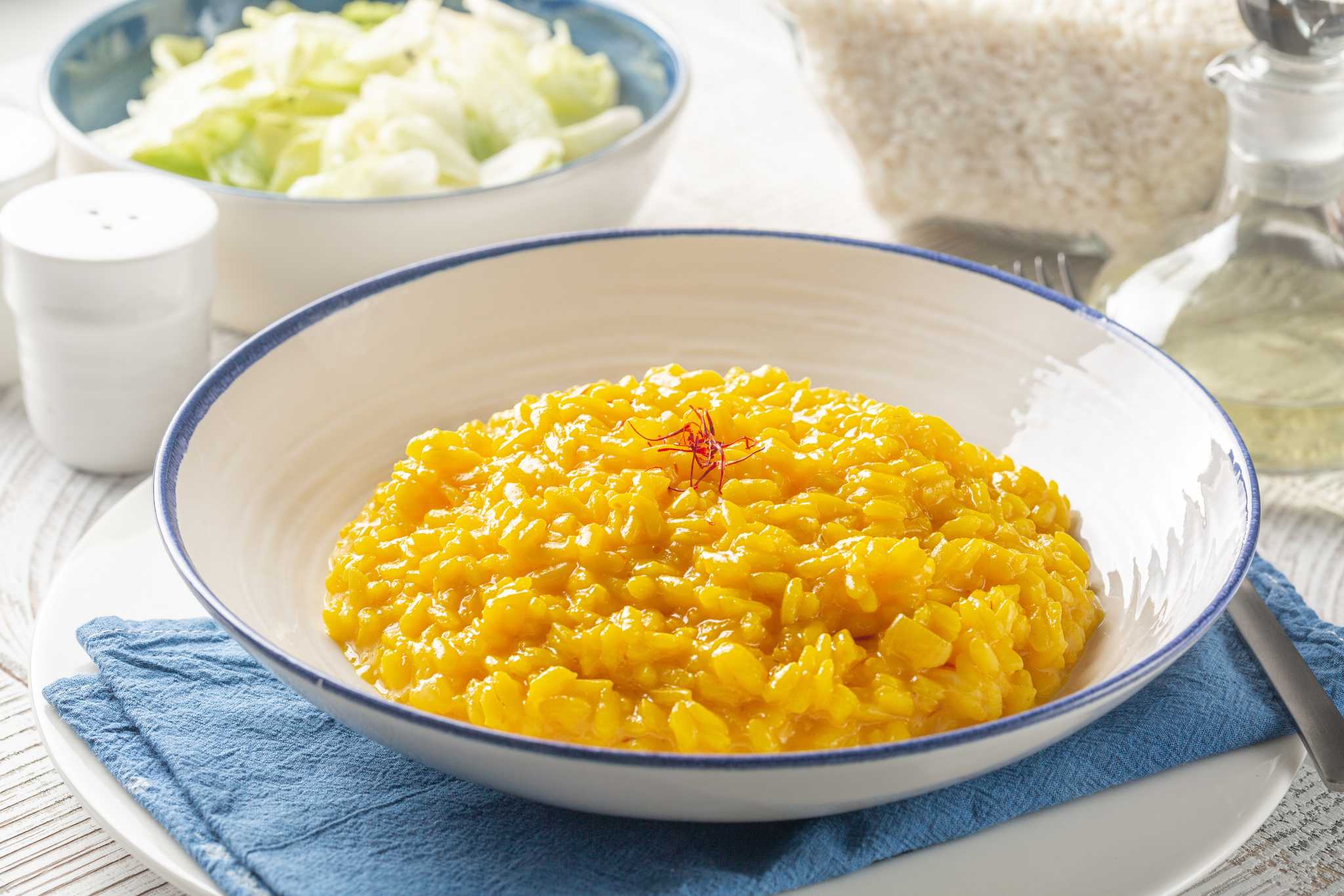 A plate of bright yellow risotto topped with a few saffron threads.