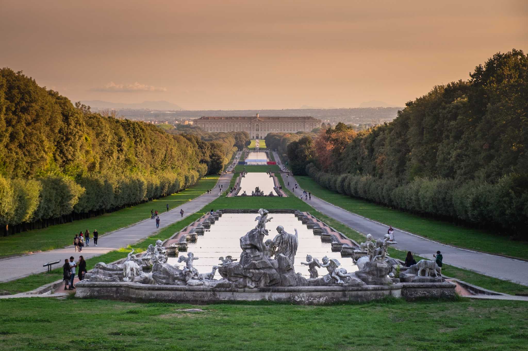 Fountains and long garden canal leading to the Royal Palace of Caserta at dusk.