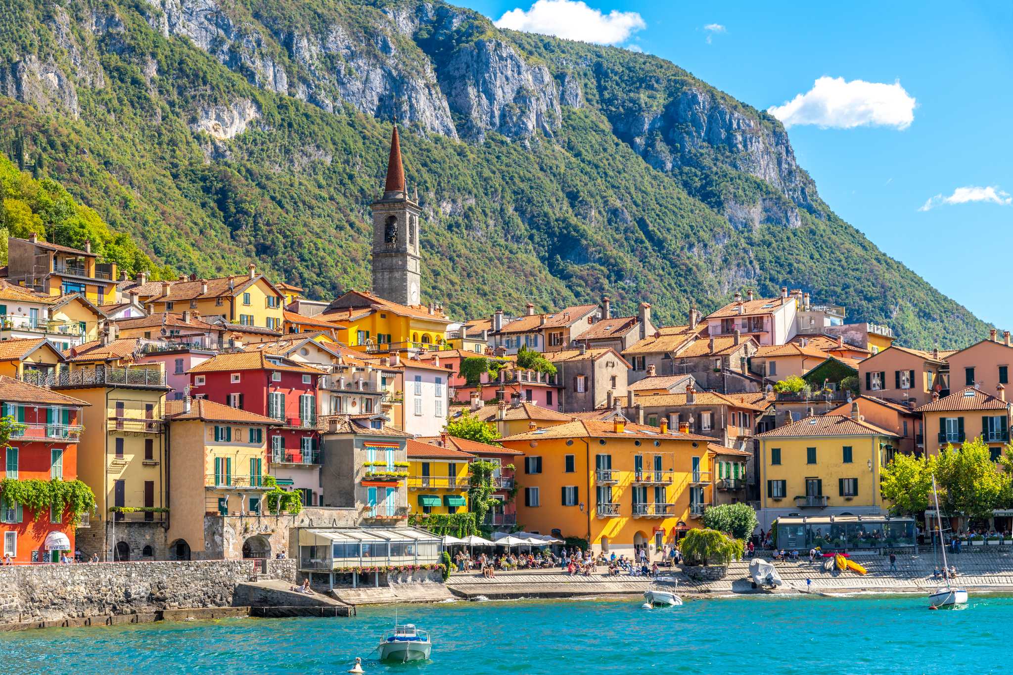 Varenna's colorful houses along the shore of Lake Como, a bell tower and steep mountain rising behind them.