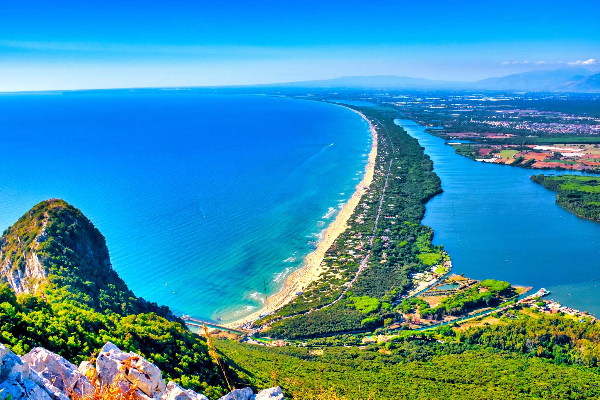 Sabaudia's dune beach curving between the blue sea and its lagoon.
