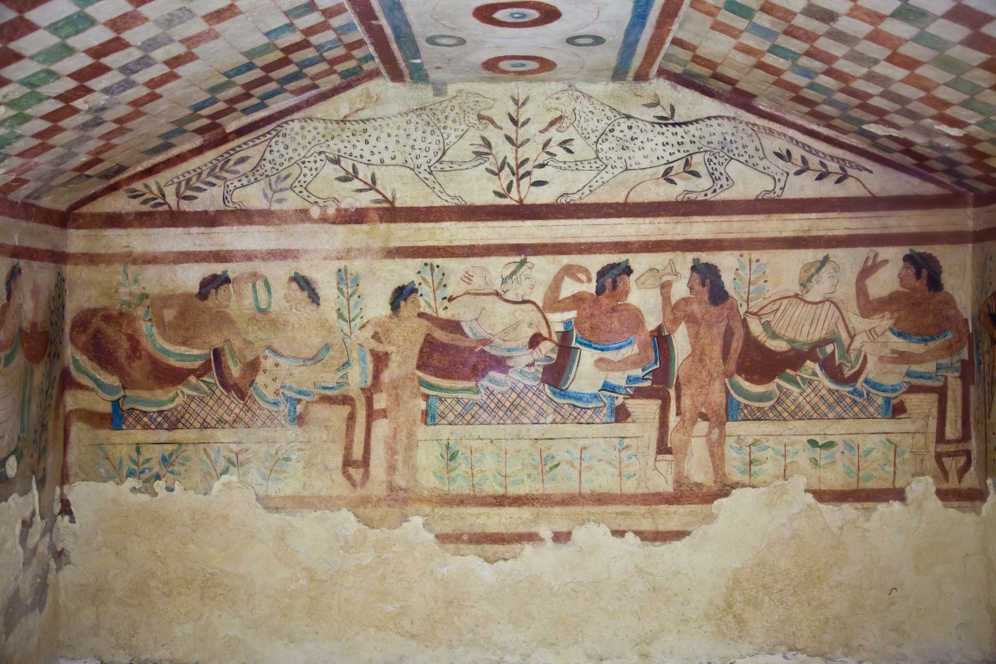 Fresco with reclining figures at a banquet, decorated ceiling, and two leopards above, from an Etruscan tomb.