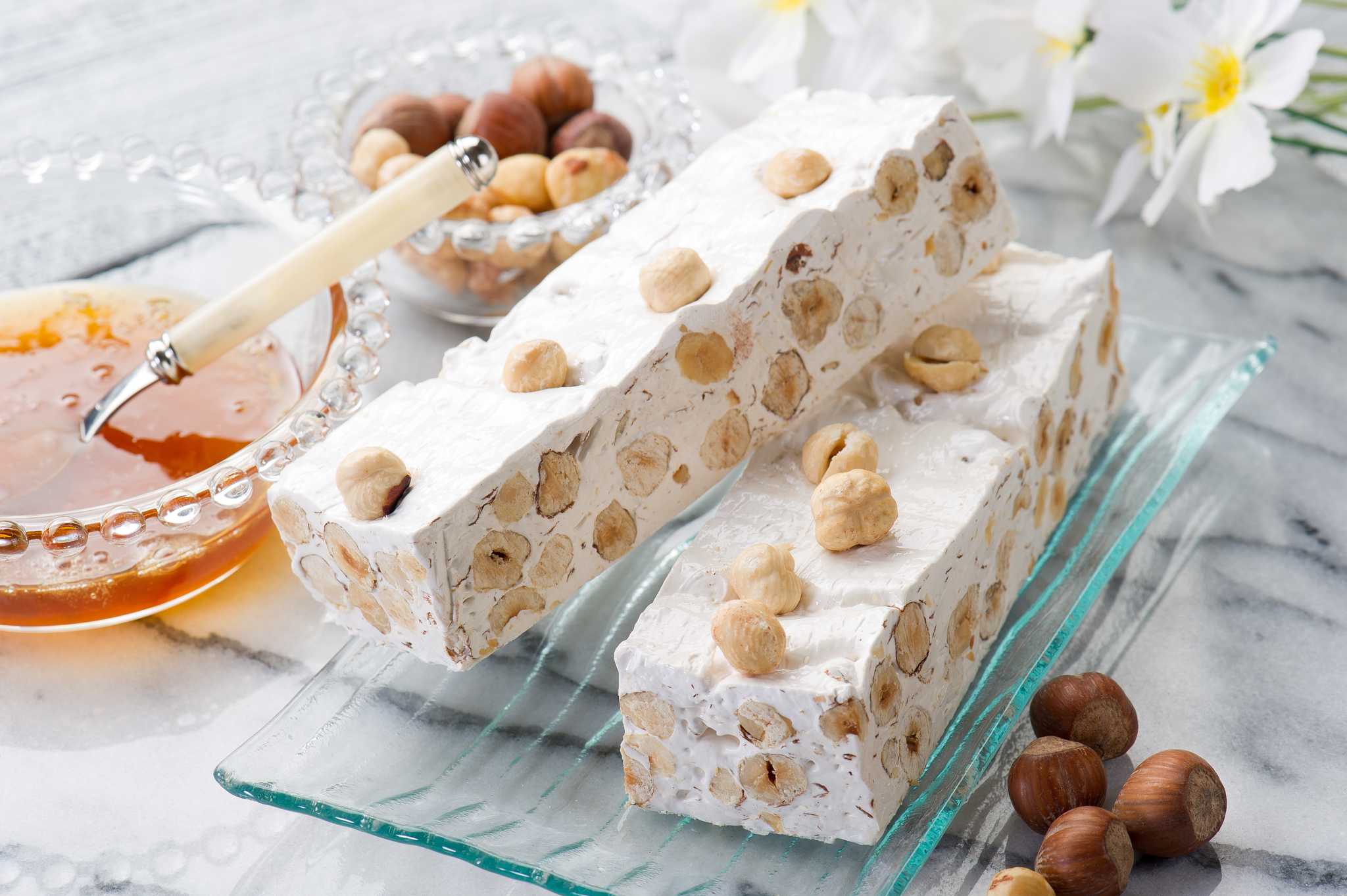Two blocks of white torrone nougat packed with whole hazelnuts, showing the dense texture.