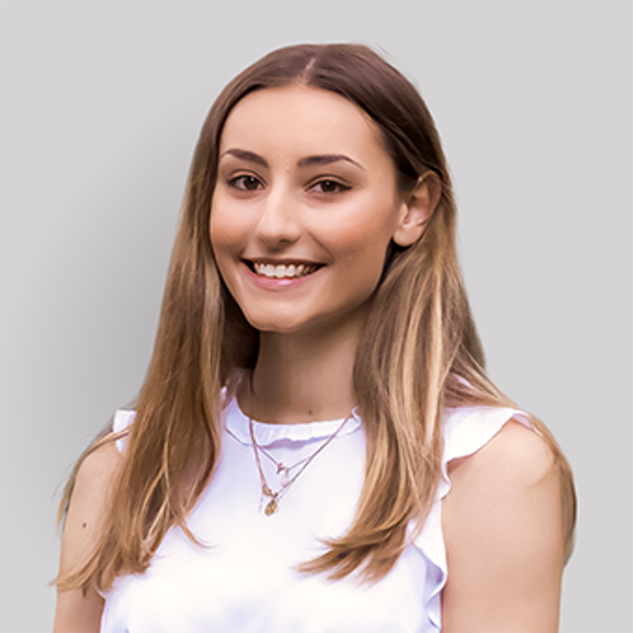 A brunette woman in a white shirt looks at the camera.