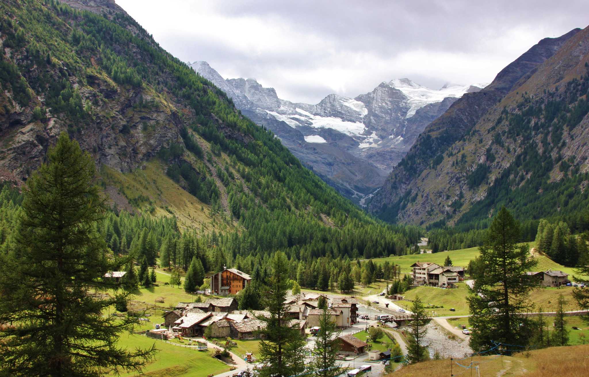 Aerial view of small valley village in Gran Paradiso National Park with evergreen trees.