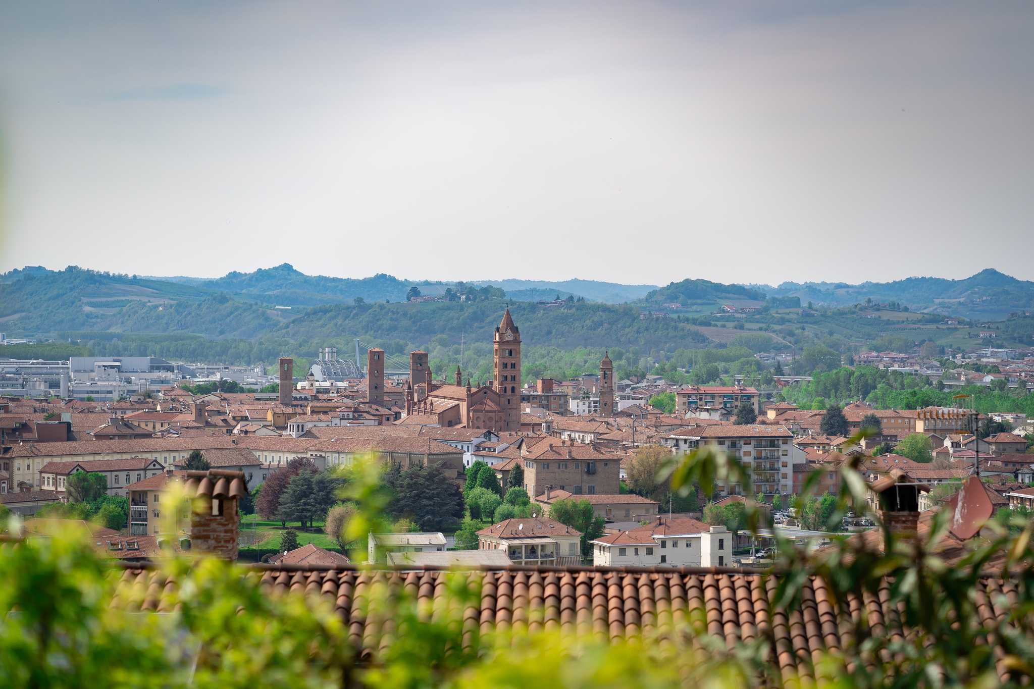 Alba skyline of red-roofed buildings in front of distant foggy hills.