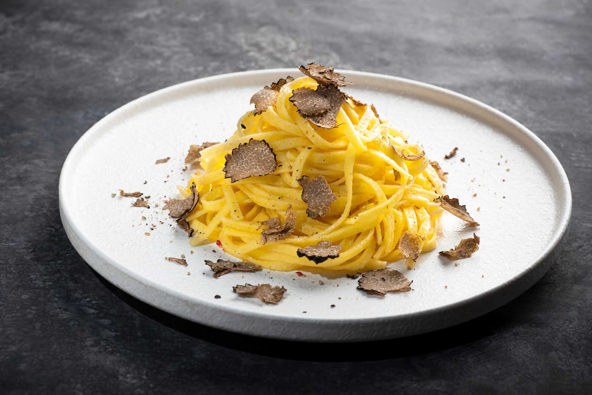 Plate of simple pasta topped with finely shaved black truffle.