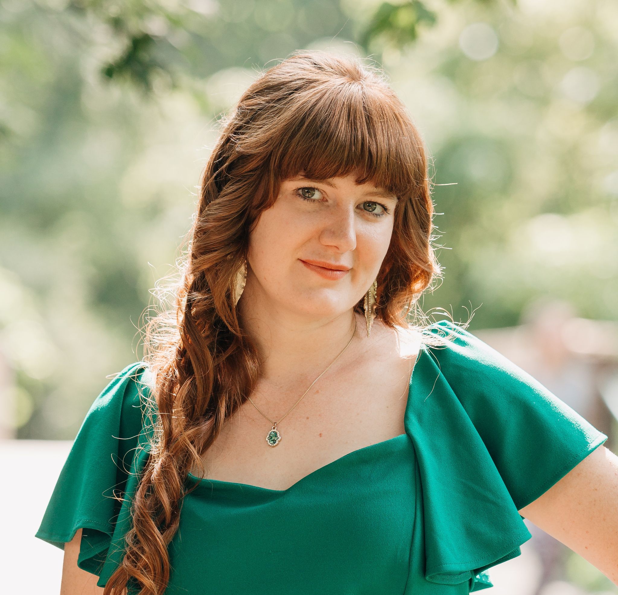 A close-up of a woman in a green dress looking at the camera.
