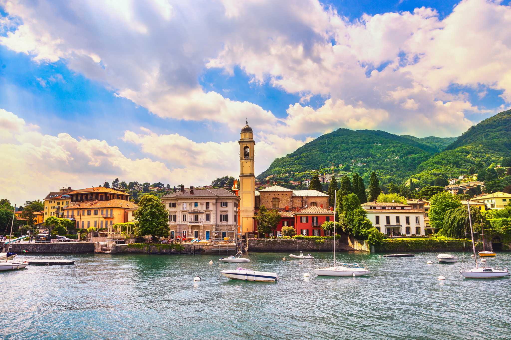 Cernobbio's bell tower and waterfront villas above boats moored on Lake Como.