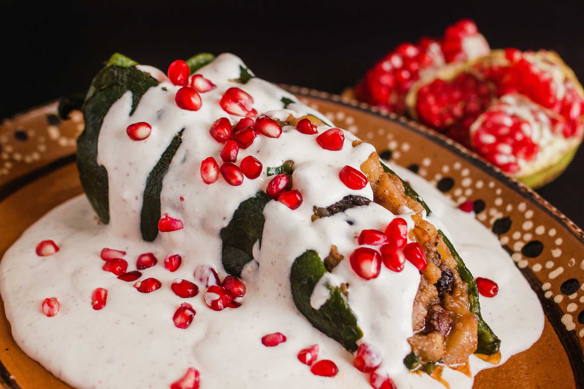 Stuffed chile en nogada with white cream sauce and topped with pomegranate seeds.