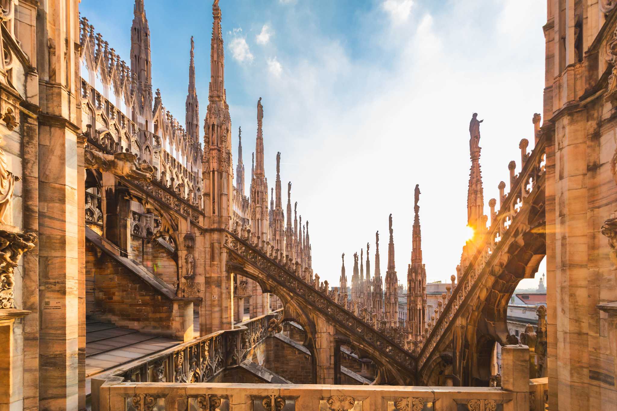 The gothic details of the spires on Milan’s Duomo roof against a blue sky.