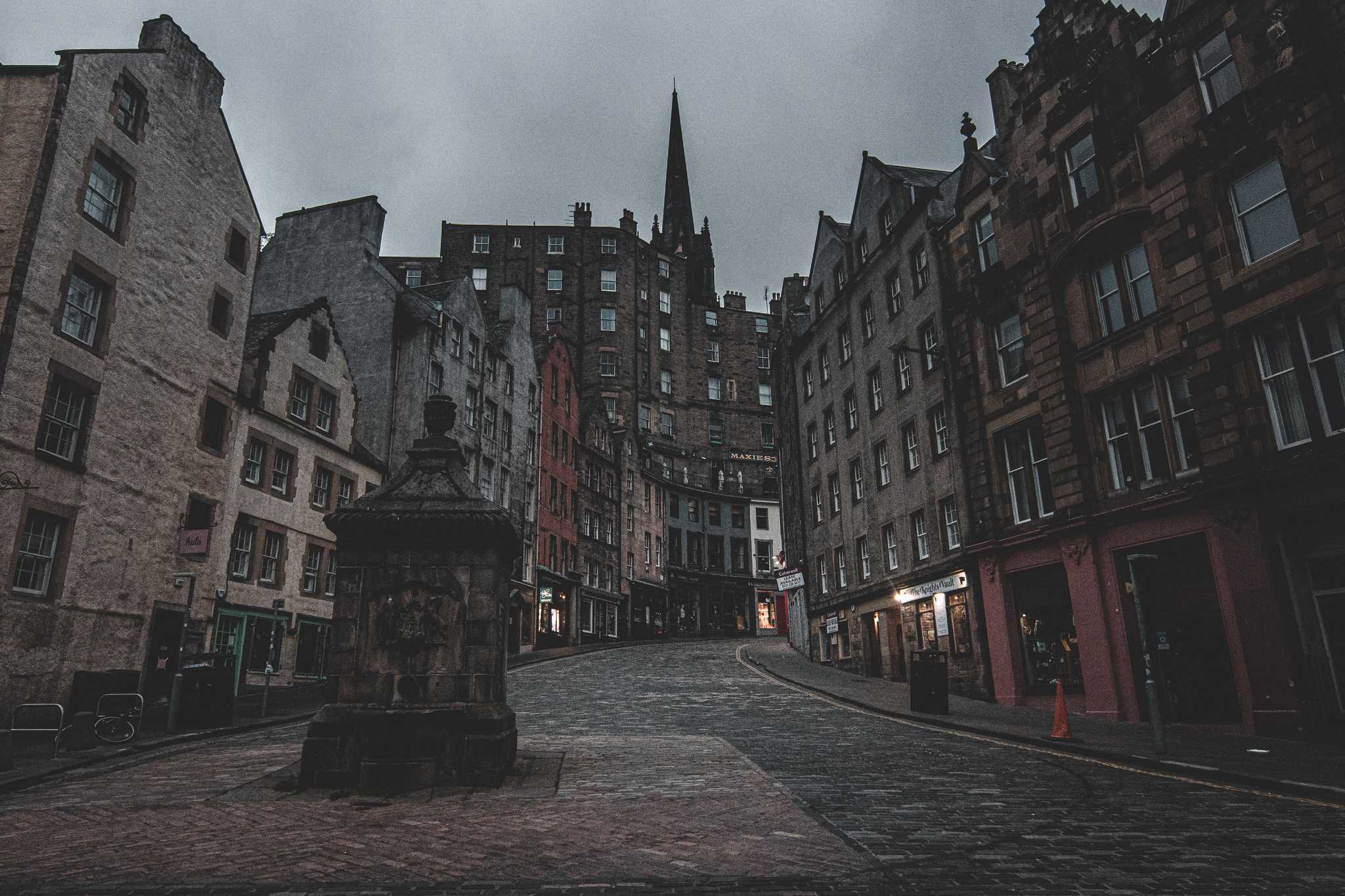 A dark photo of a winding cobblestone alley in Edinburgh, Scotland.