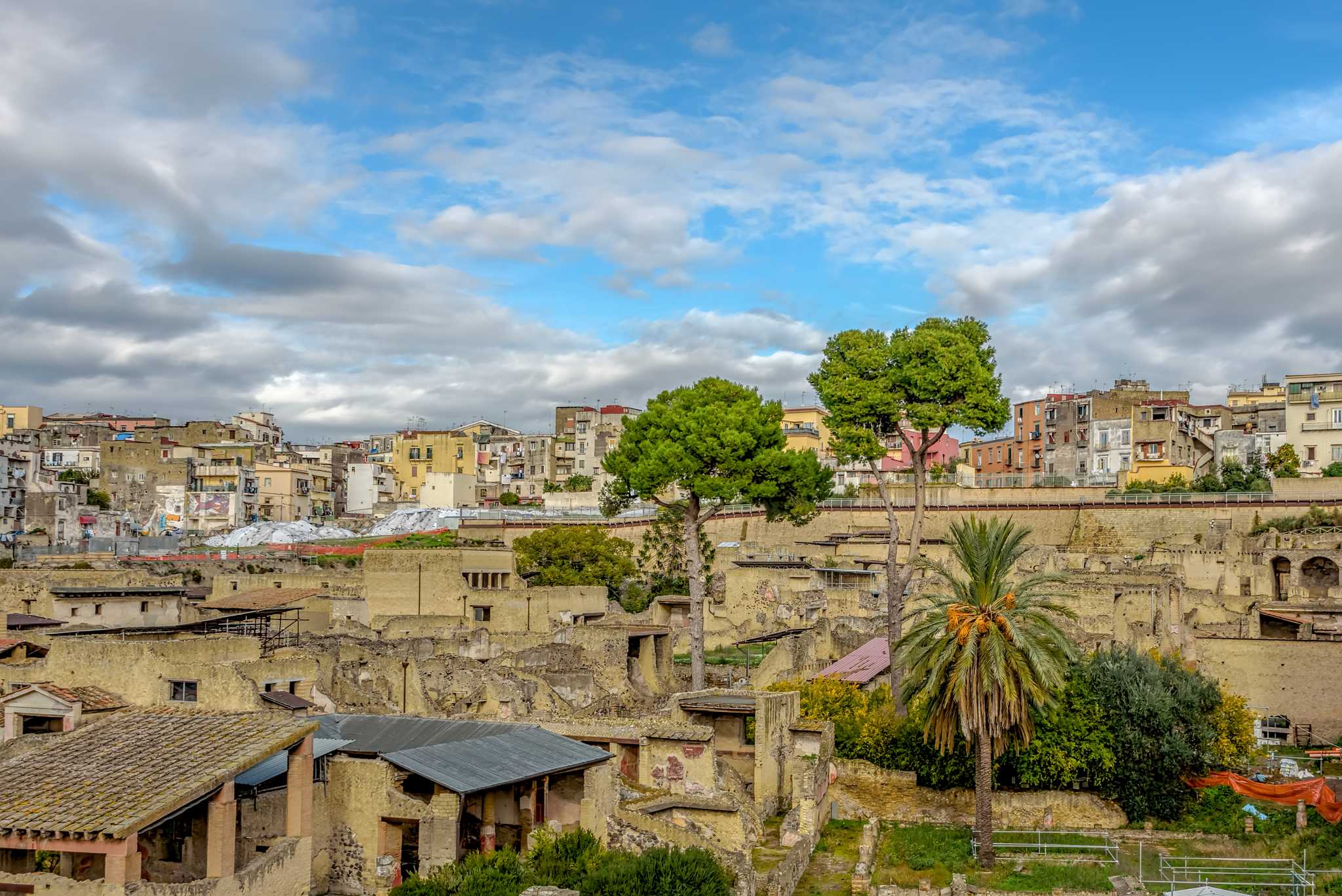 Excavated Roman ruins of Herculaneum in Ercolano, sunk below the modern town rising behind.