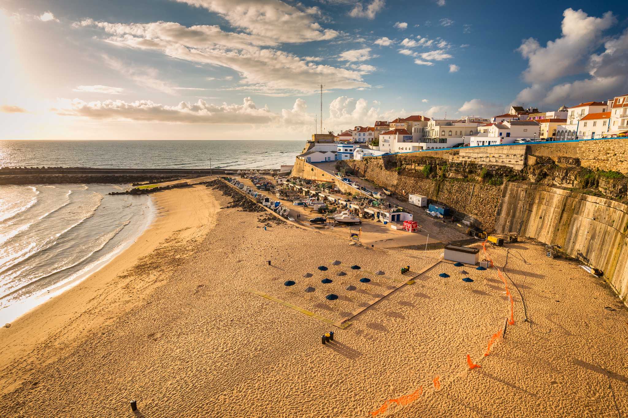 The sandy beach of Ericeira, poised with dry-docked boats and beach umbrellas.