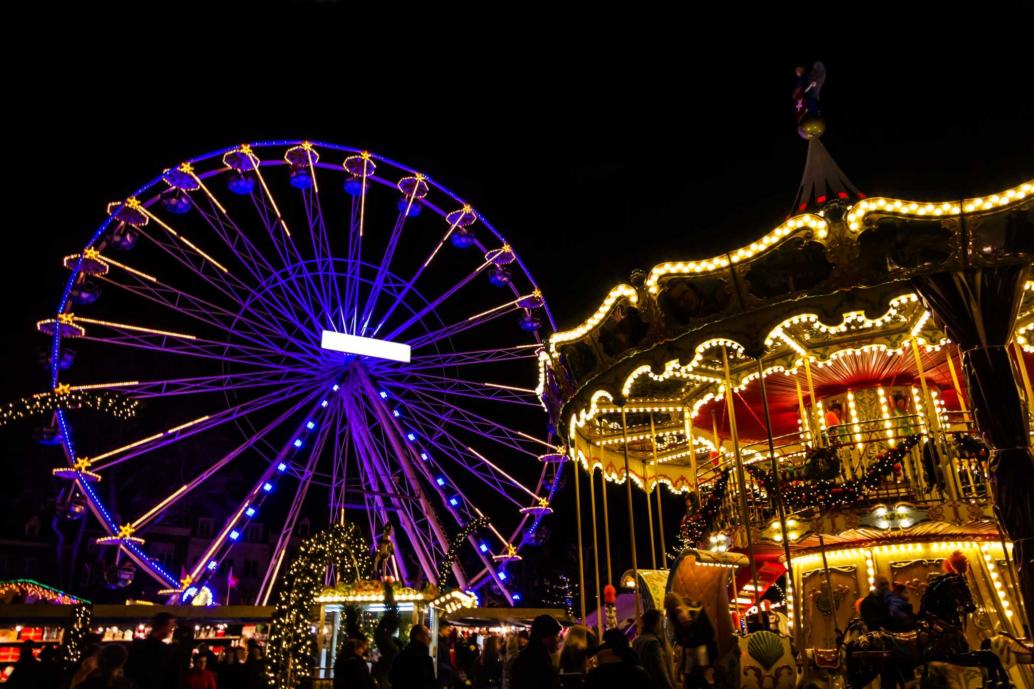 Colorful lighted Ferris wheel and carousel in Maastricht at Christmas time.