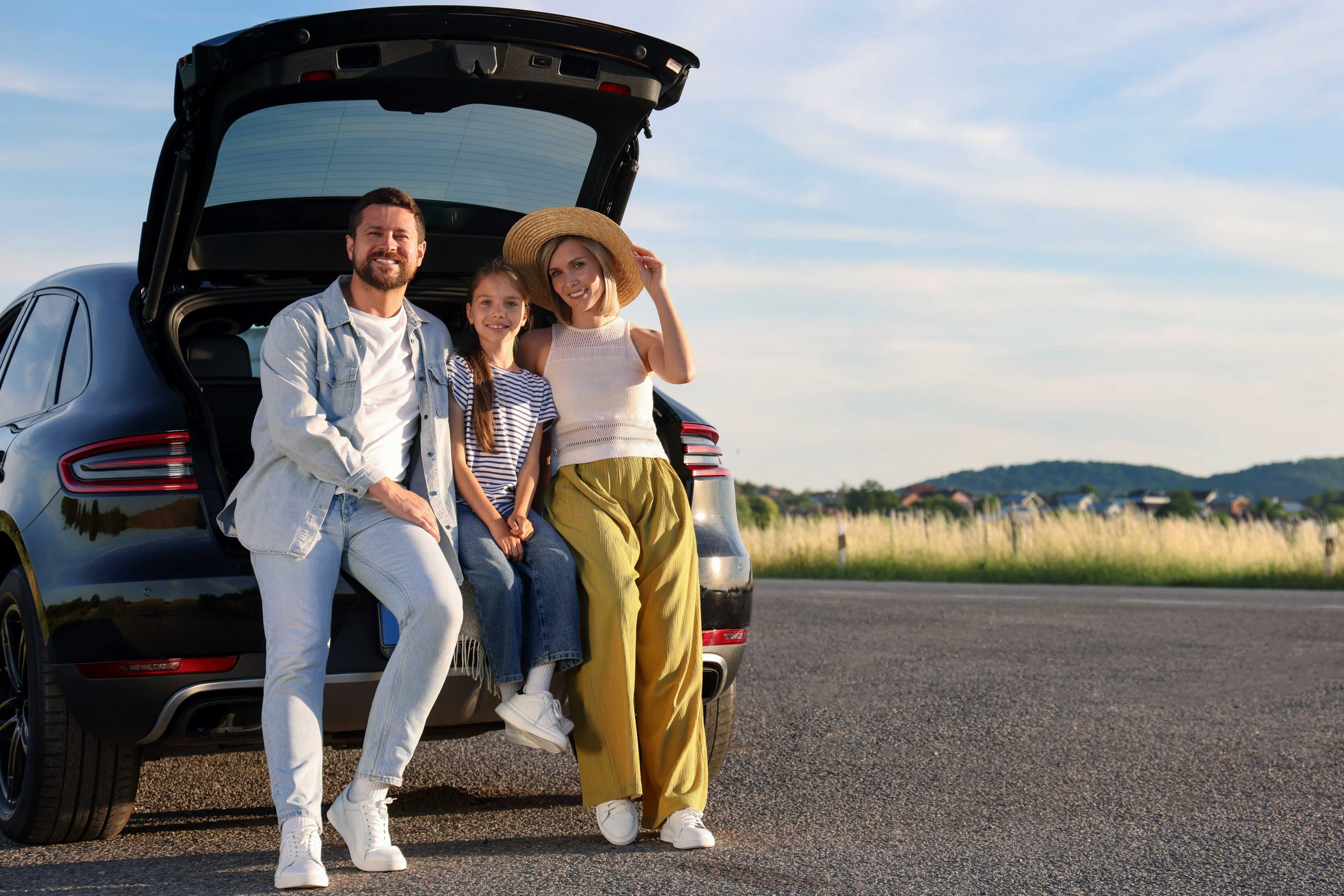 A family with children in front of a car
