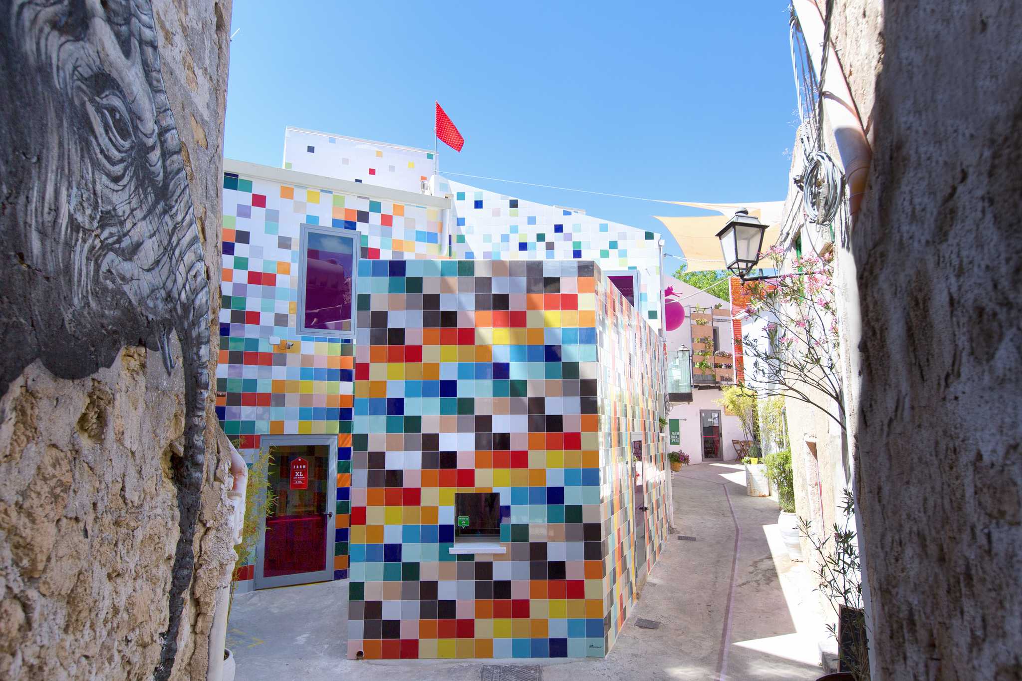 Building clad in multicolored tiles at the end of a narrow stone alley.