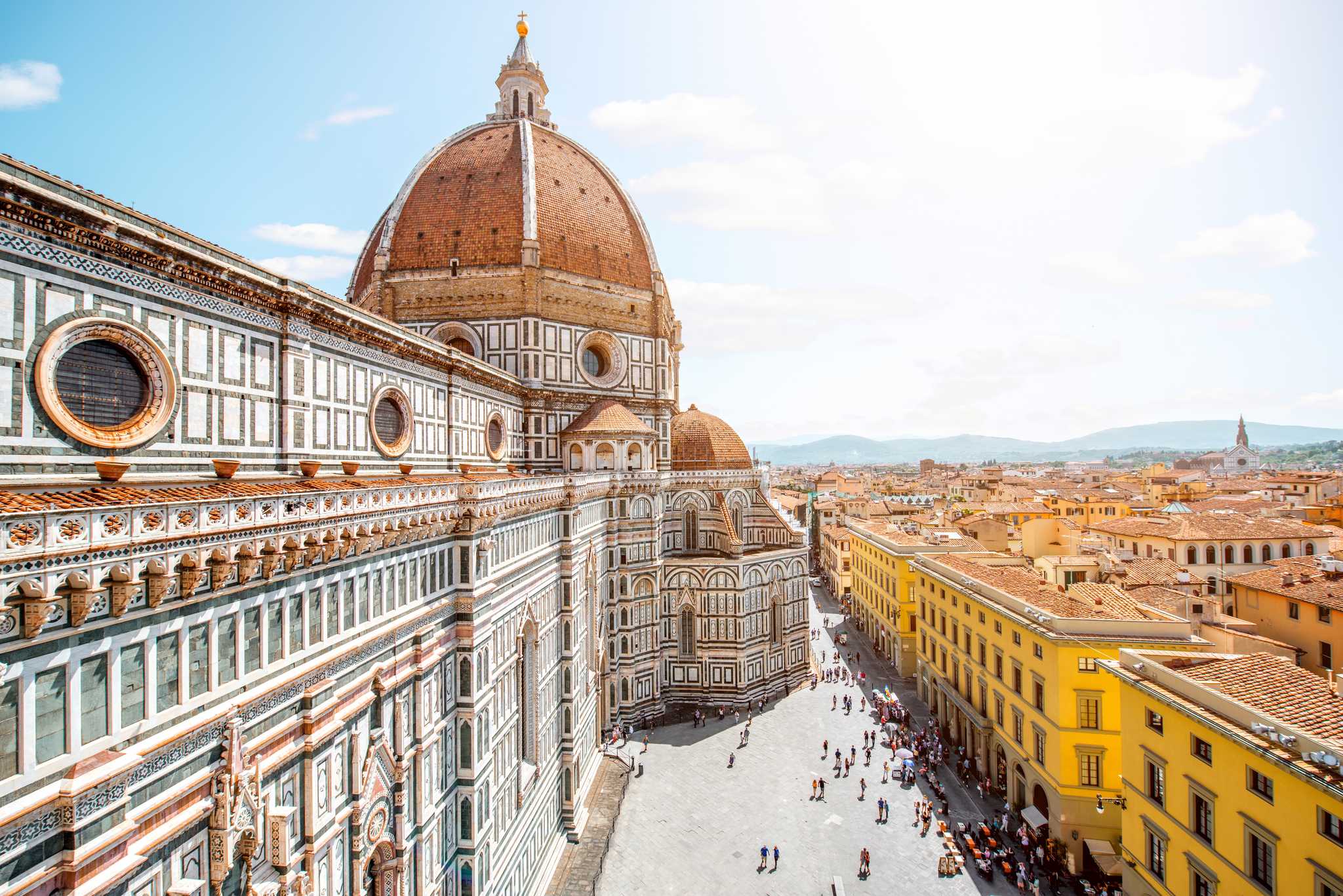 Florence’s Duomo on the left, with bright yellow buildings on the right side.