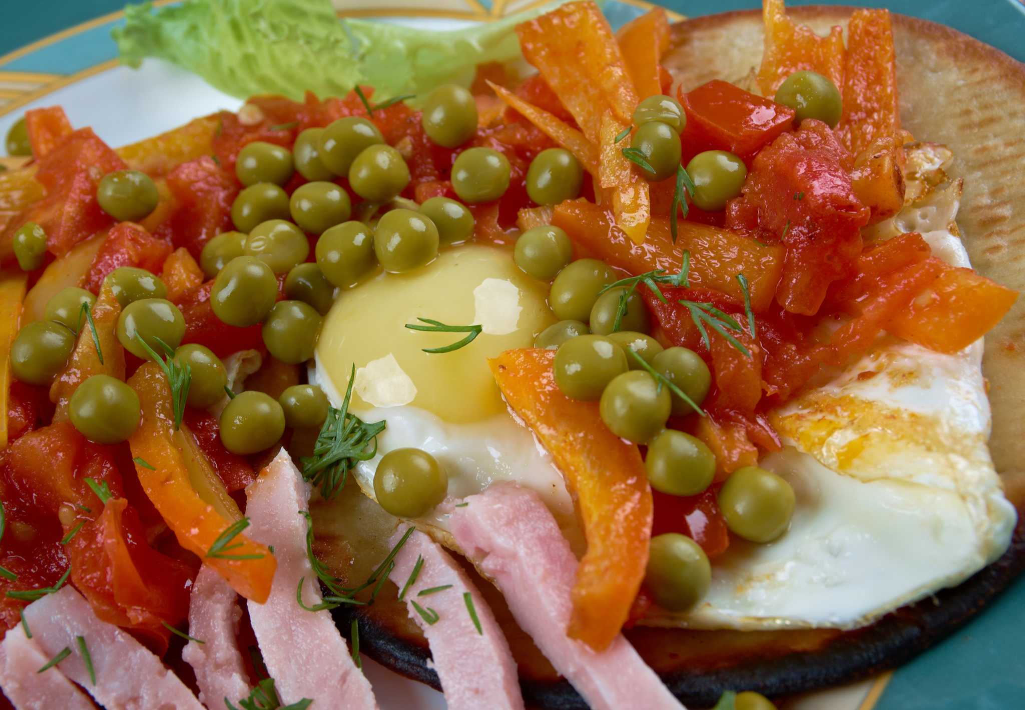 Eggs served with peas, peppers, ham, and salsa in traditional Yucatán style.