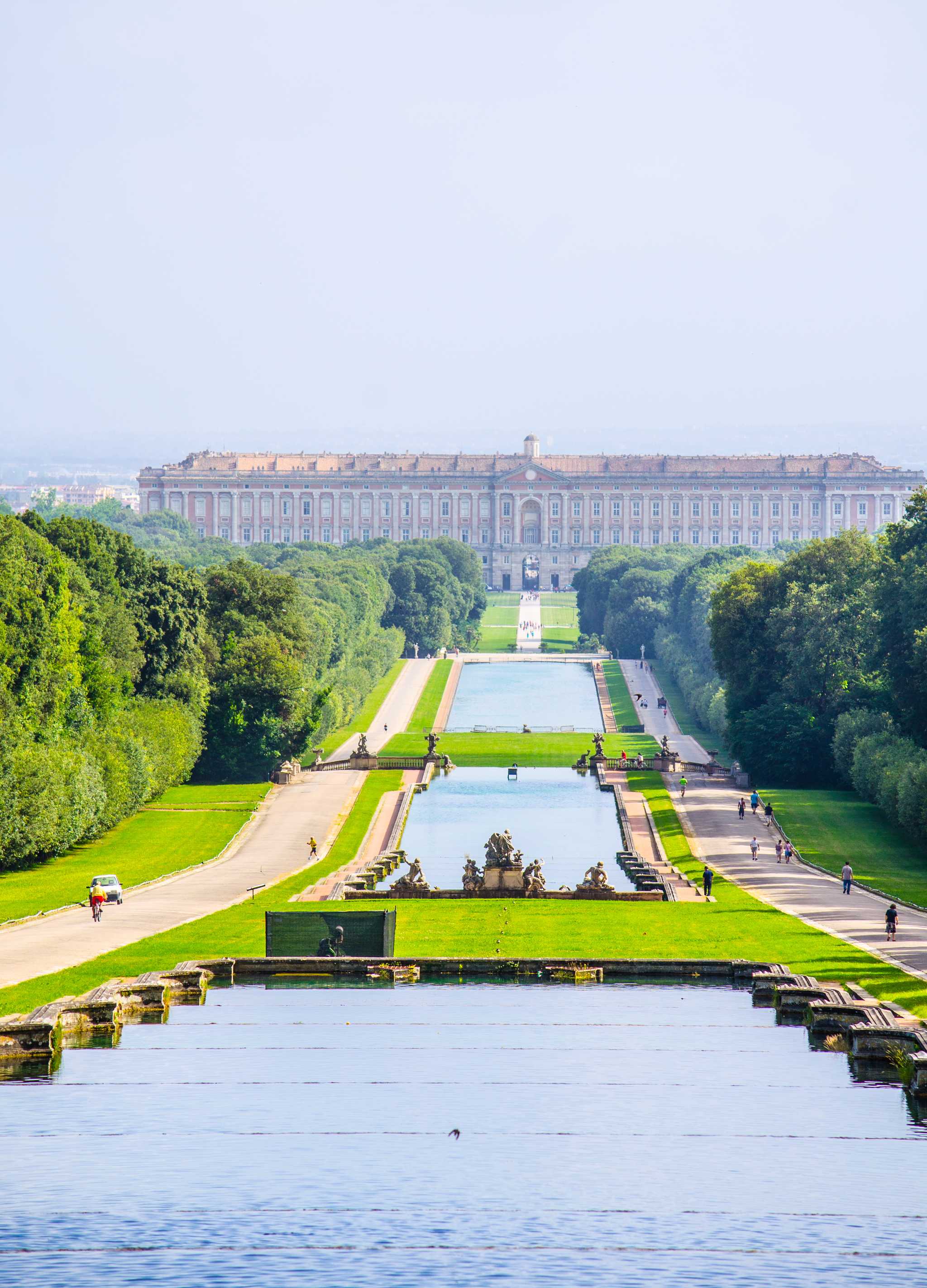 Reflecting pools leading to the elaborate palace of Caserta, framed symmetrically by paths and greenery.