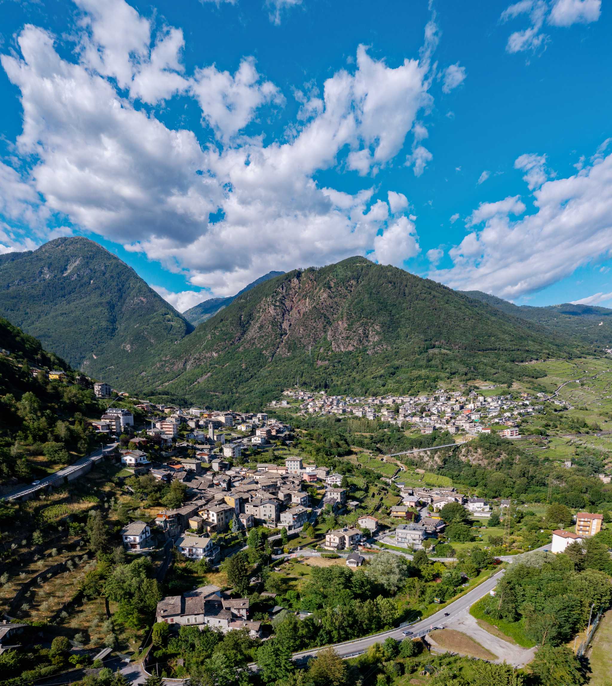 Aerial view of Valtellina area in Italy, green mountains behind alpine villages.
