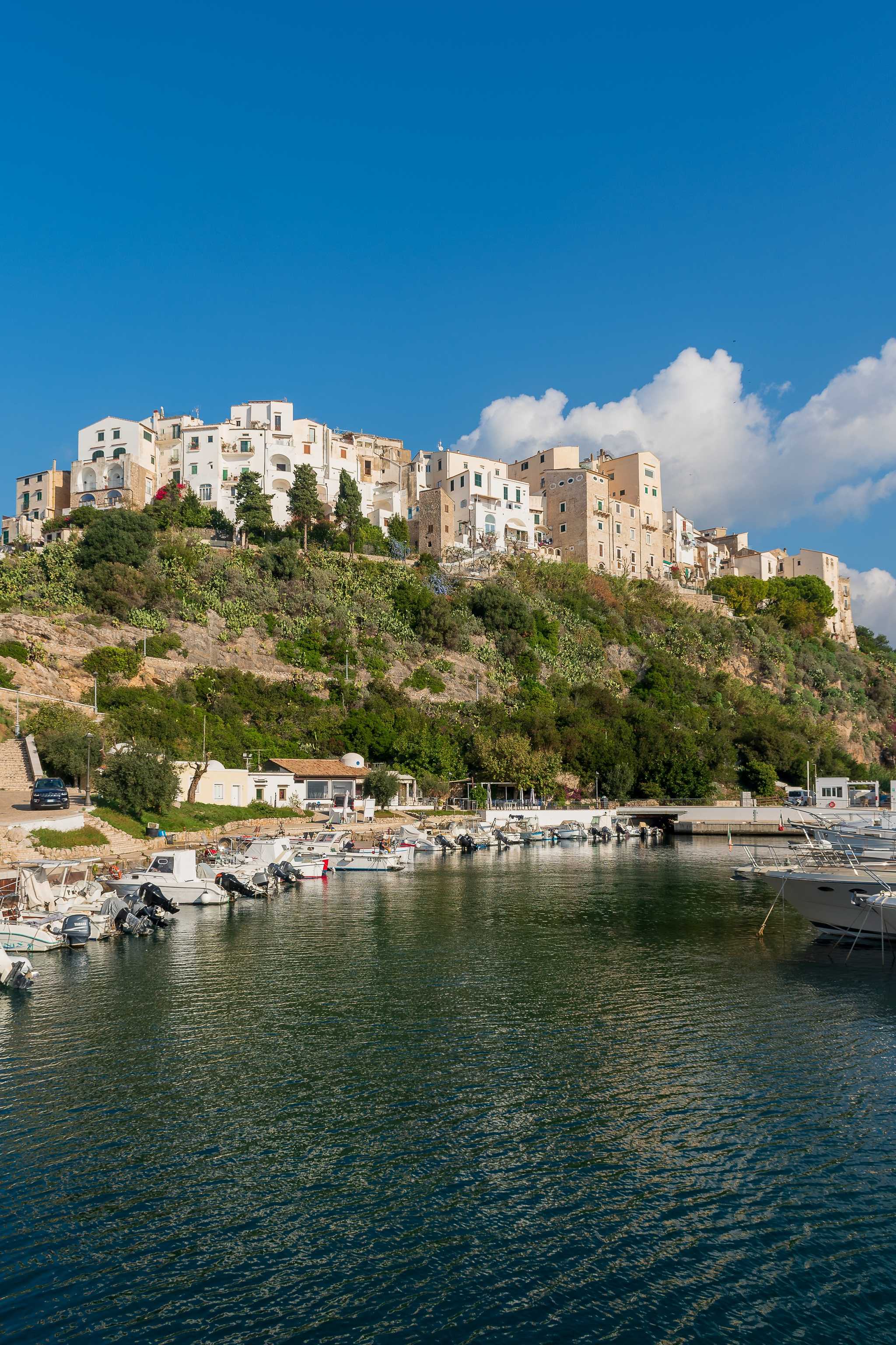 Whitewashed Sperlonga buildings on a hill overlooking the water, with boats docked in the foreground.