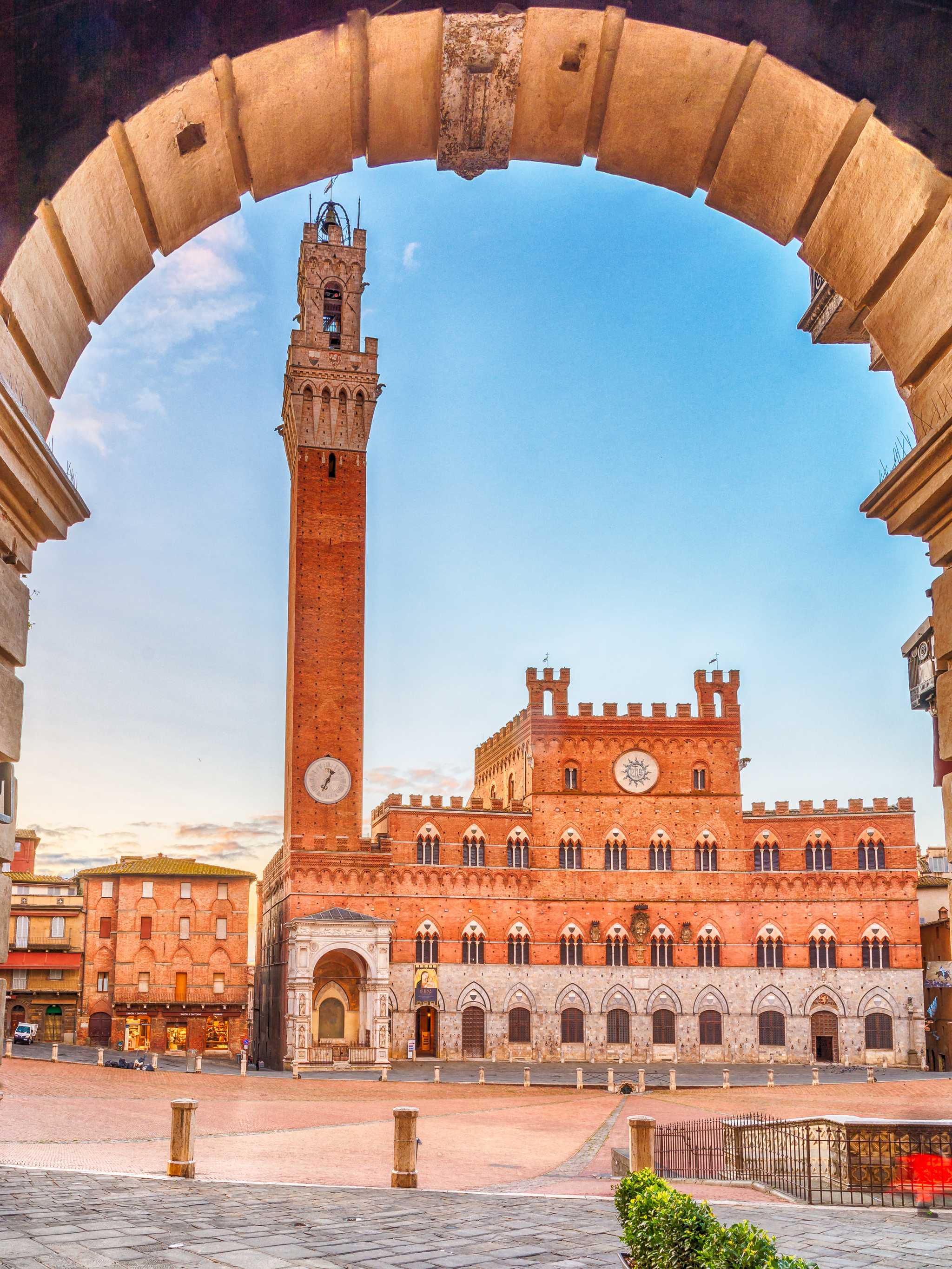A bell tower in Piazza del Campo in Siena, framed by a stone arch.