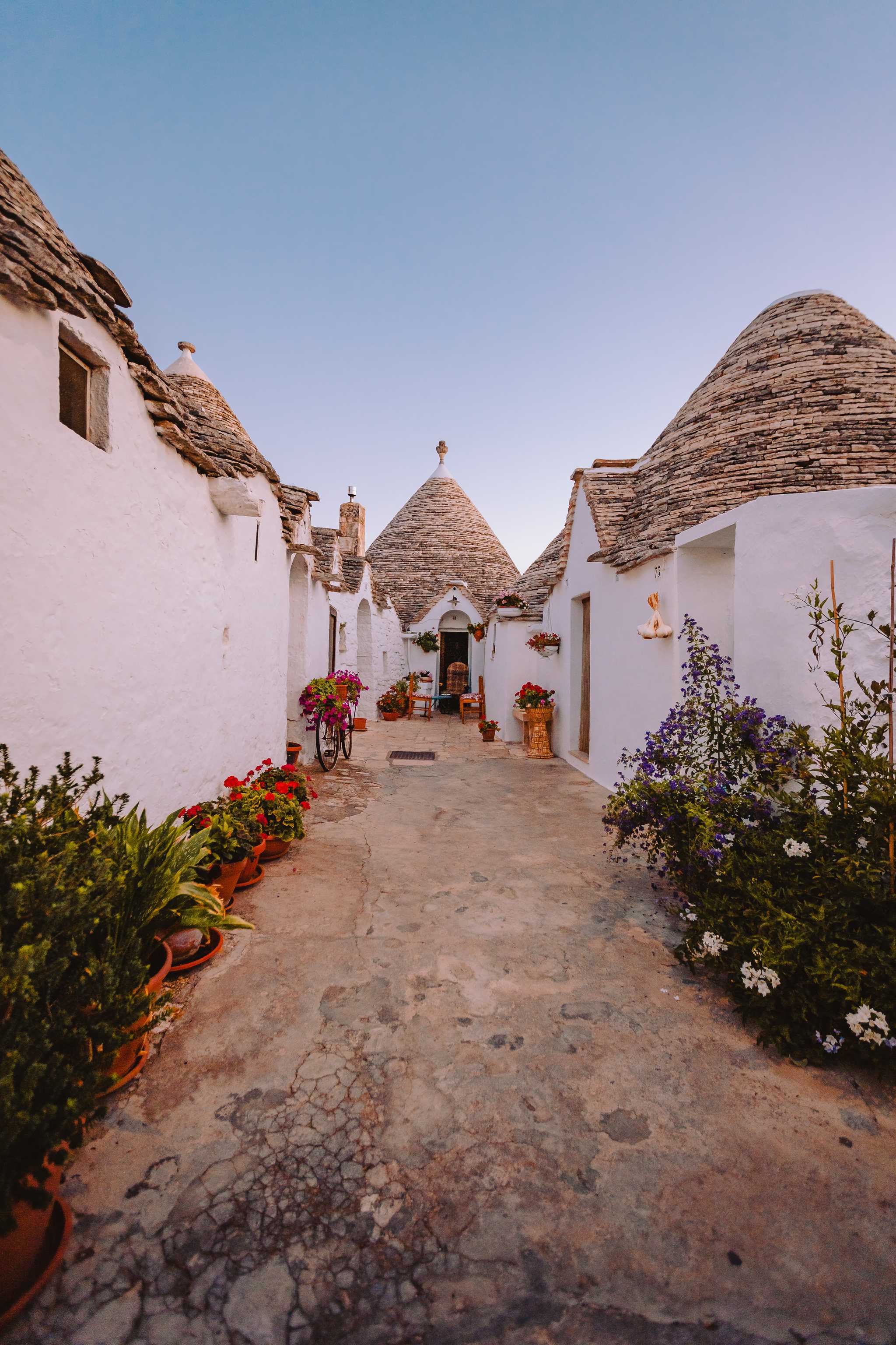 An alley of cone houses (trullo) in Alberobello at dusk.