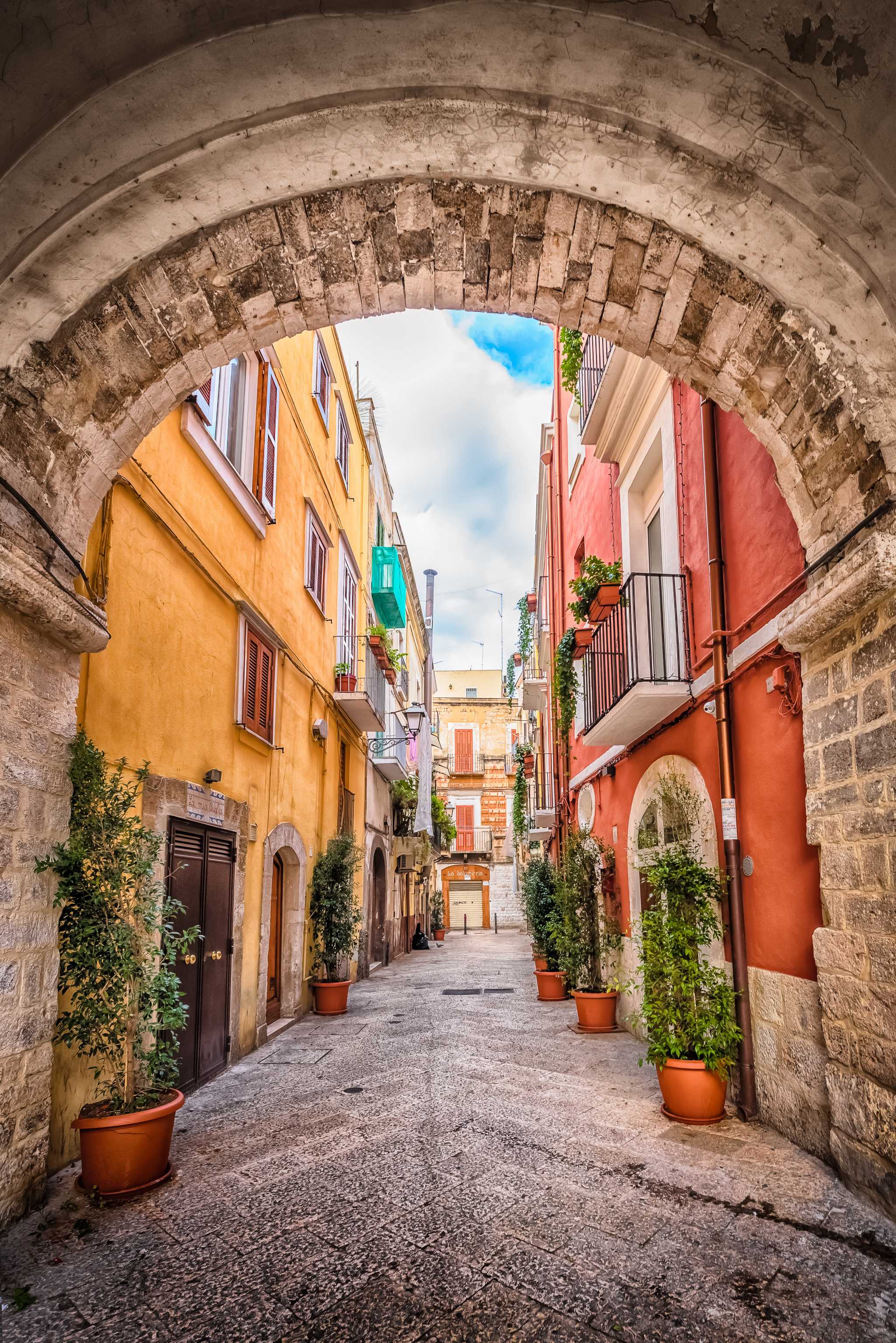 Stone archway framing an alley of colorful buildings in Bari.