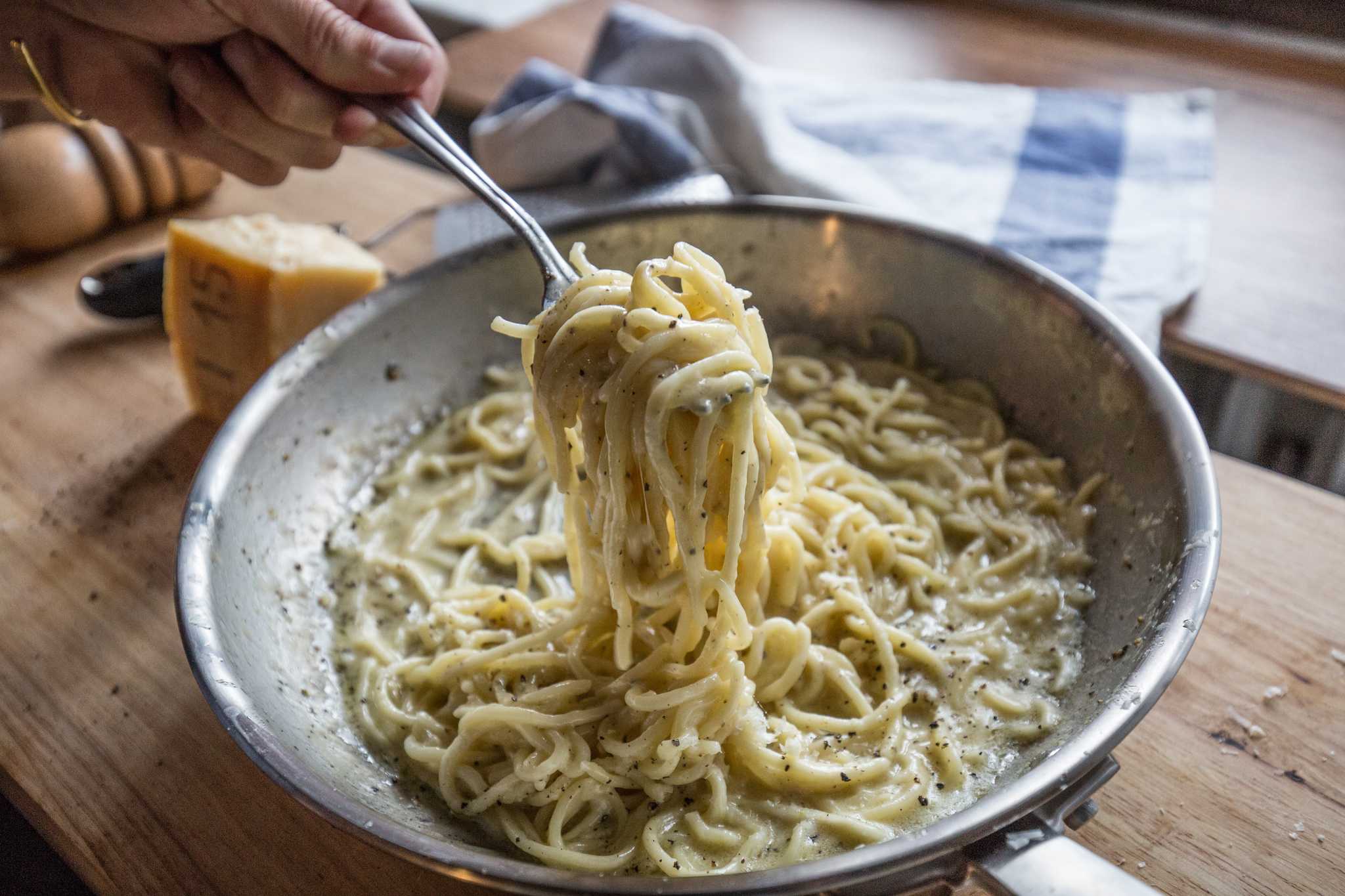 Cacio e pepe in a grey bowl being forked up.
