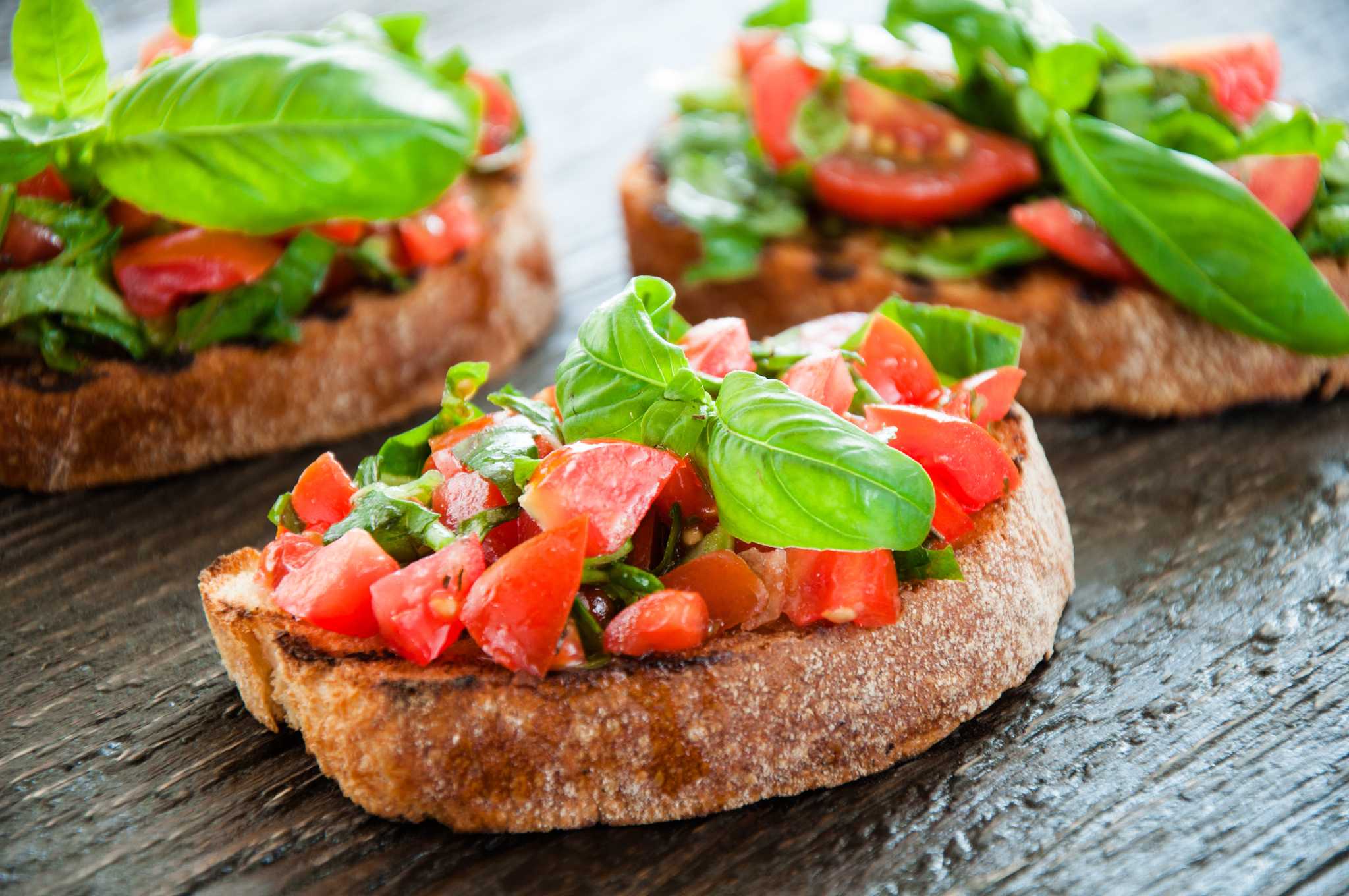 Close-up of tomato and basil bruschetta on a small slice of bread.