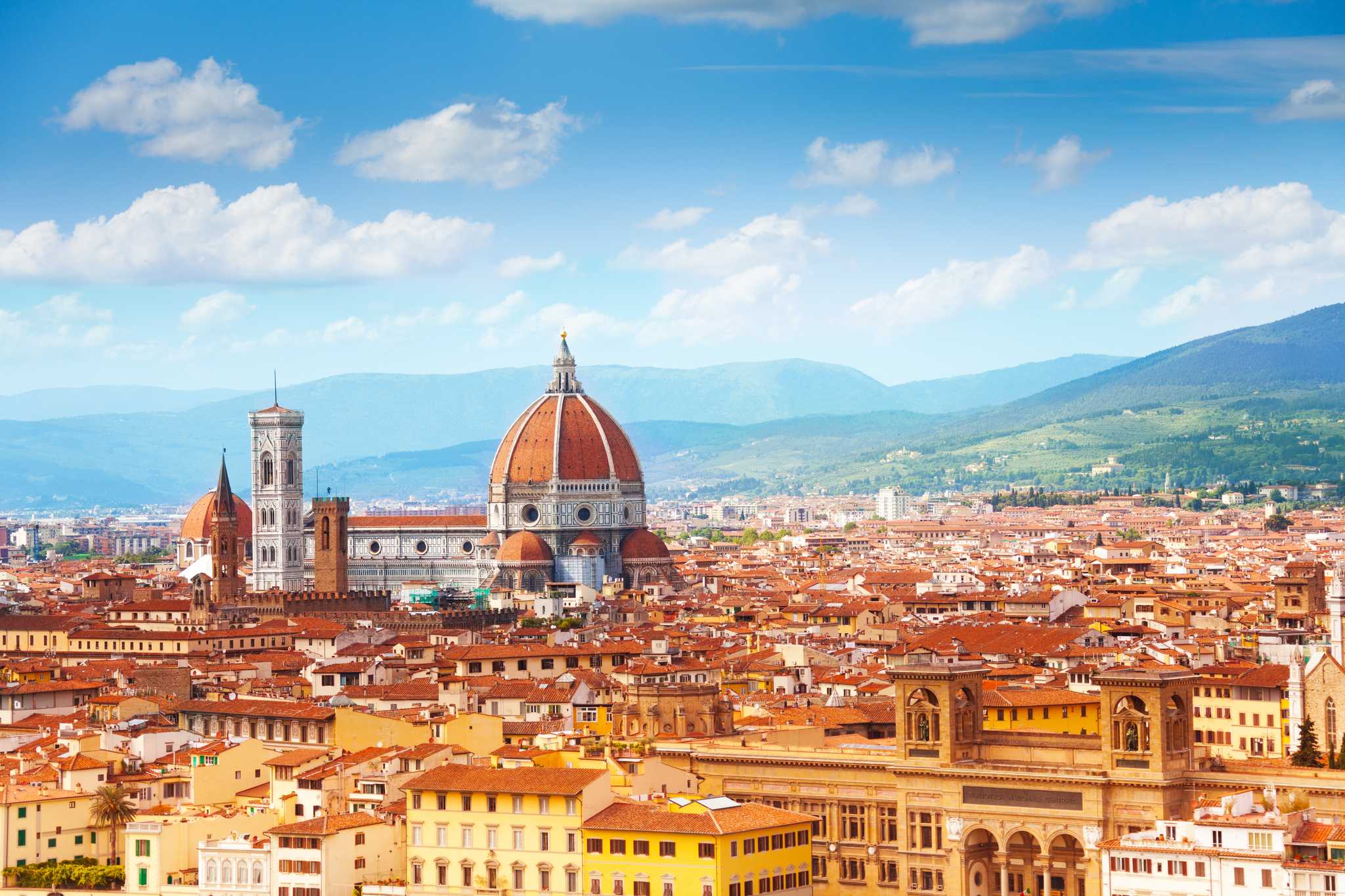 Florence skyline centered on the terracotta dome of the Duomo with mountains in the distance.