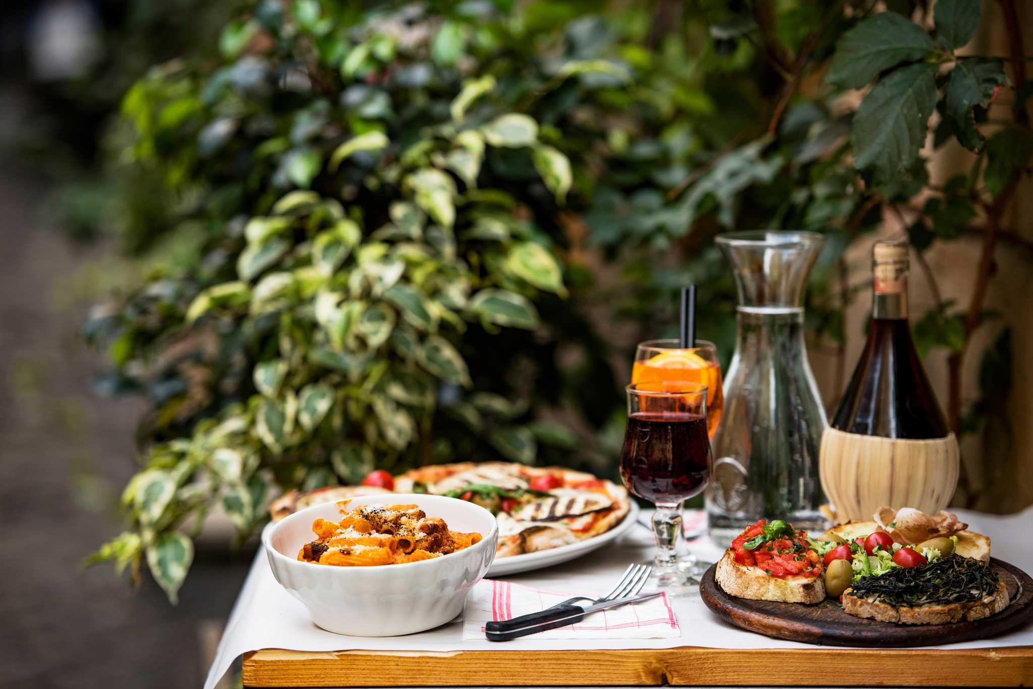 Plates of Italian food arranged on a table with red wine.