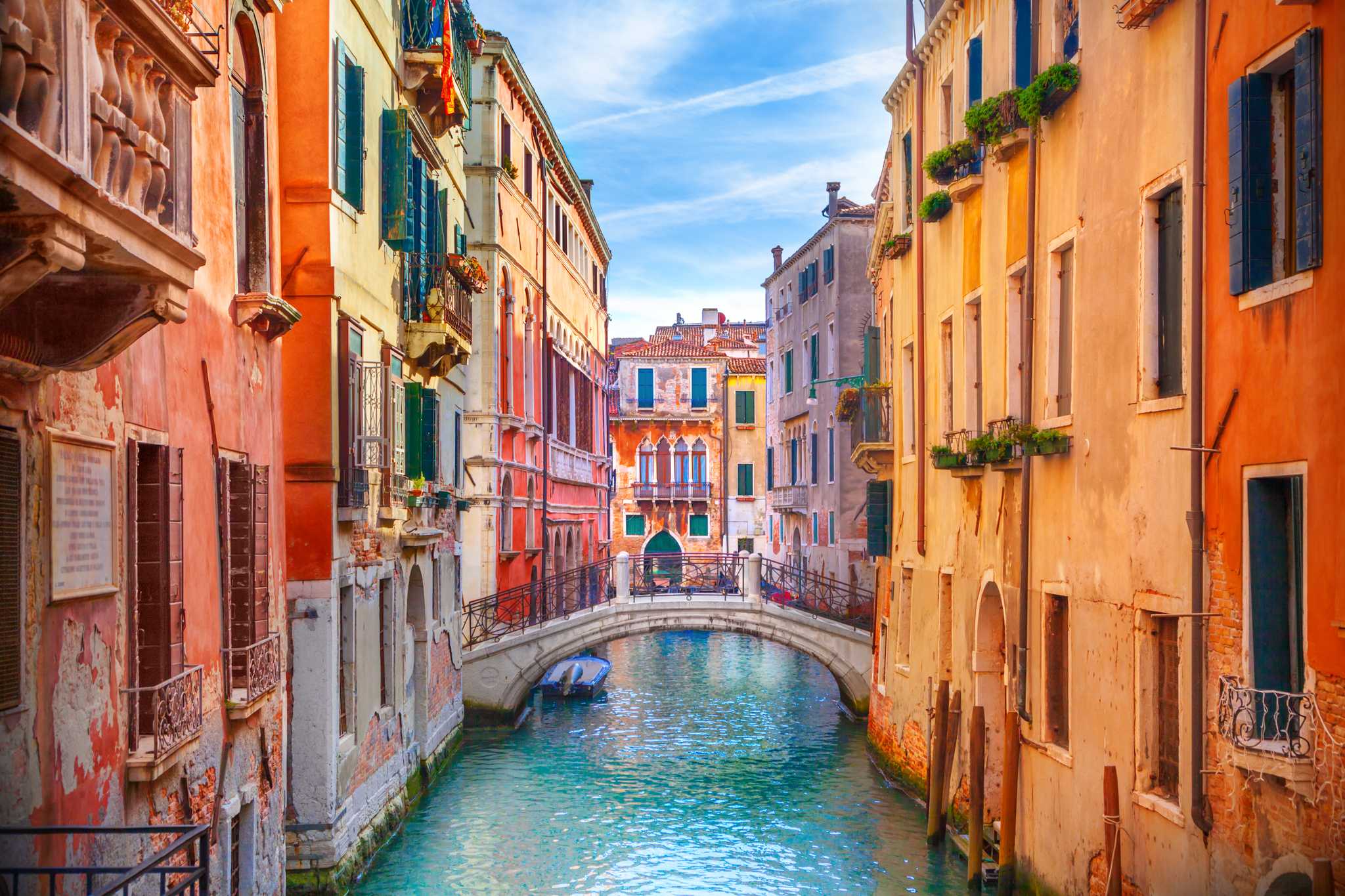 Small bridge over a narrow Venice canal surrounded by colorful buildings.