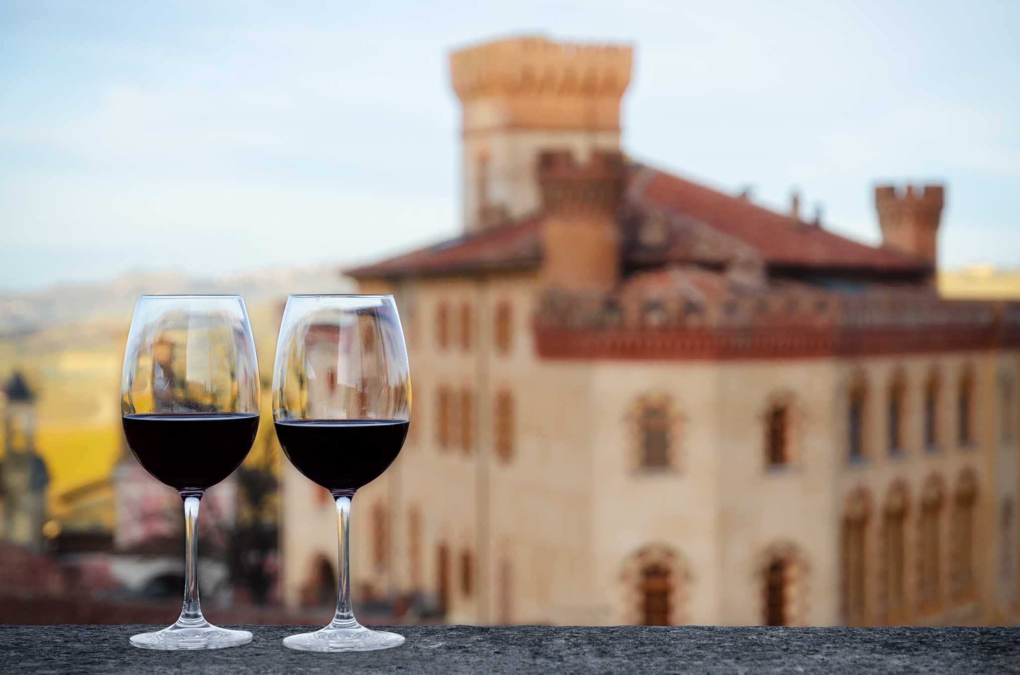 Two glasses of red wine on a ledge overlooking an Italian town.