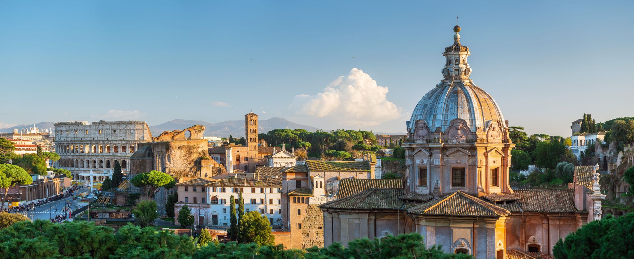 The Rome skyline at golden hour, from the Colosseum to a Baroque church dome and pines.