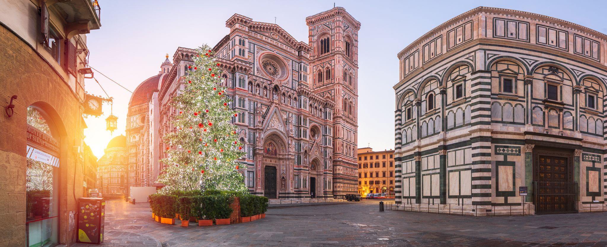 Panorama of Florence Duomo from the street, with a decorated Christmas tree in front.
