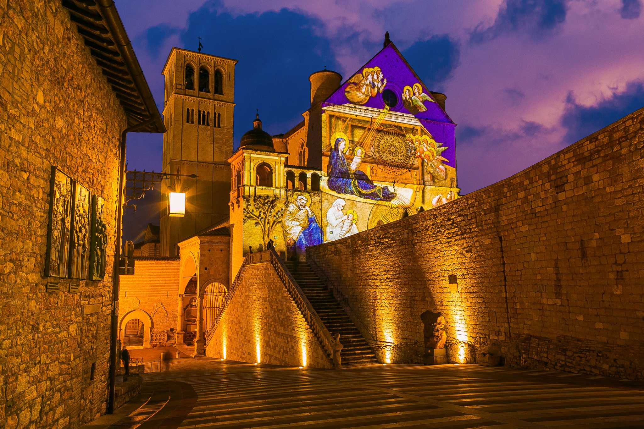 Dusk at a Cathedral in Assisi with a projection of a nativity scene on the side.