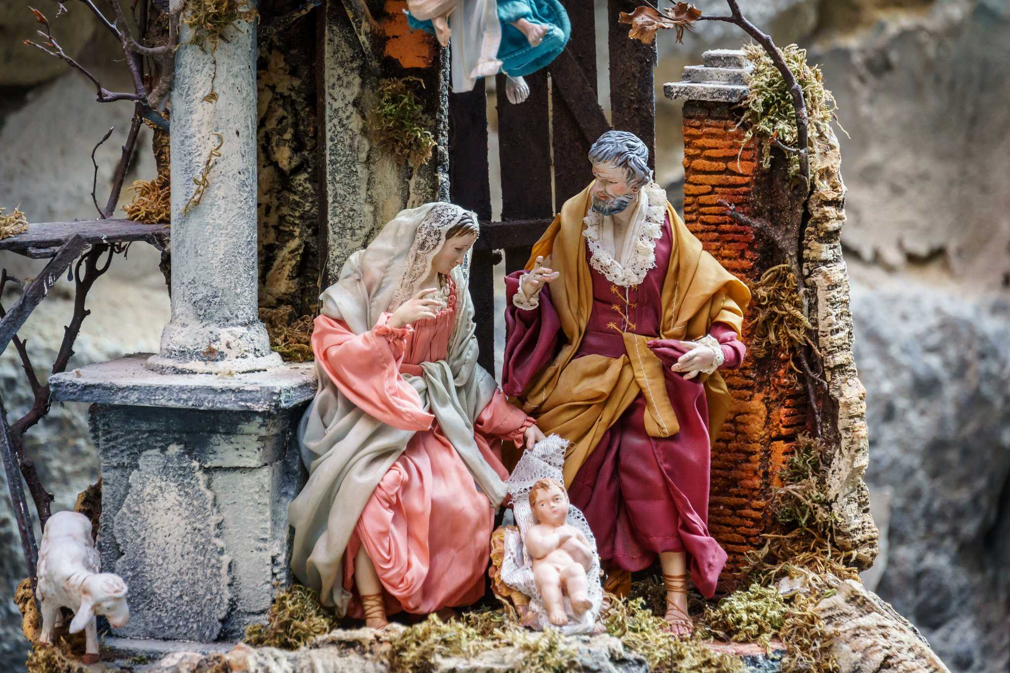 Close-up of nativity scene figurines, with the baby Jesus figure in a cradle at the front.