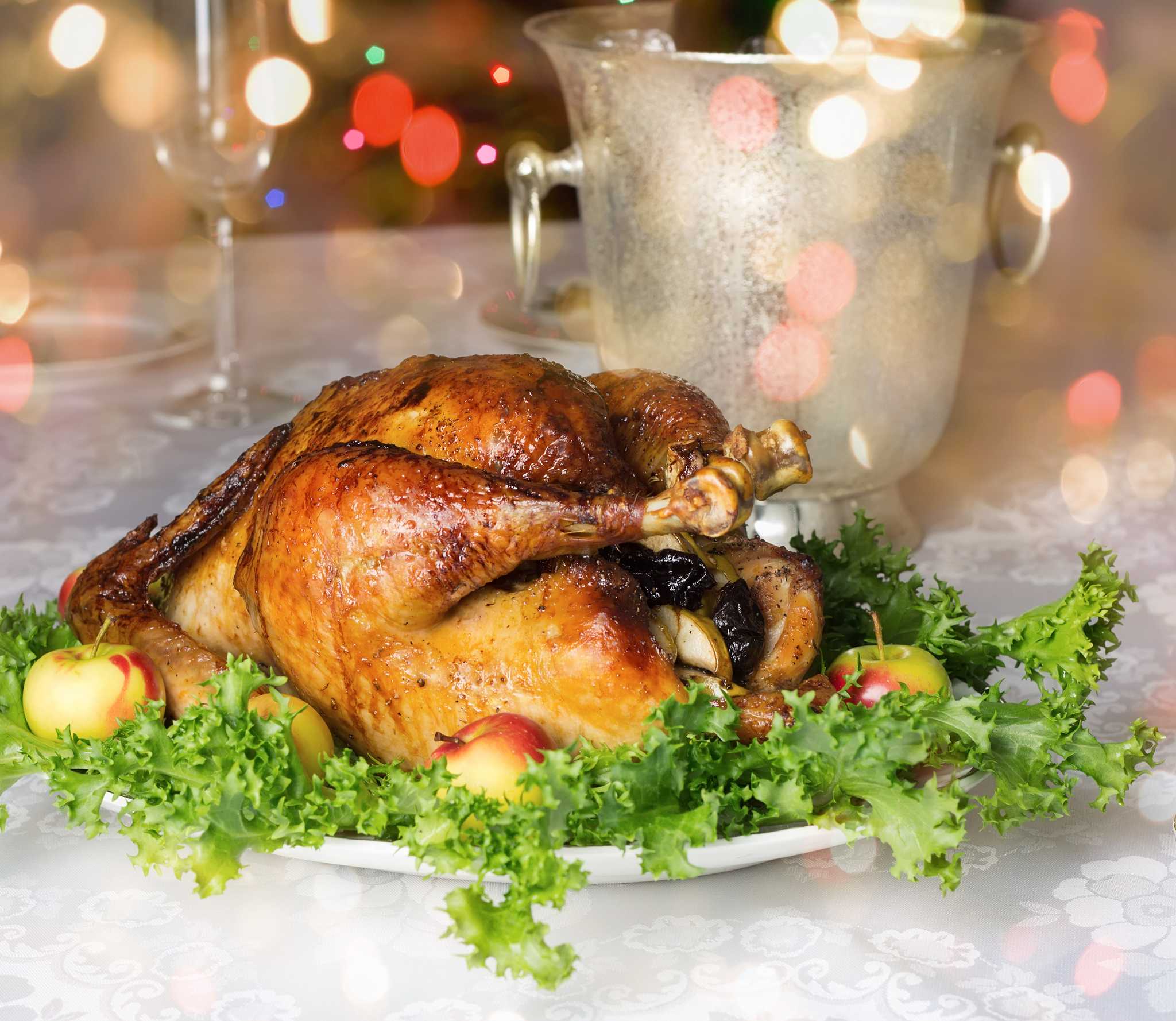 Roasted stuffed capon on a bed of lettuce with bokeh lights in the background.