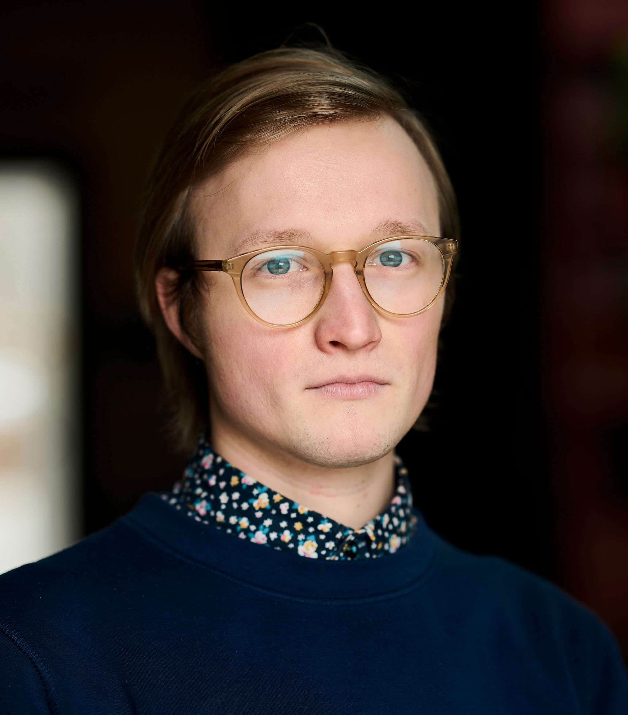 Photo of a person with short light blond-brown hair and round translucent glasses.